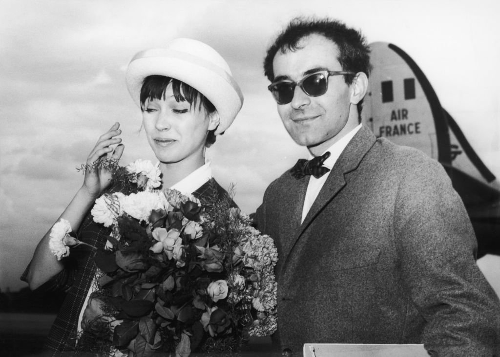 Le réalisateur français Jean-Luc Godard arrivant à l'aéroport de Berlin avec sa femme, l'actrice danoise Anna Karina, le 28 juin 1961. | Photo : Getty Images