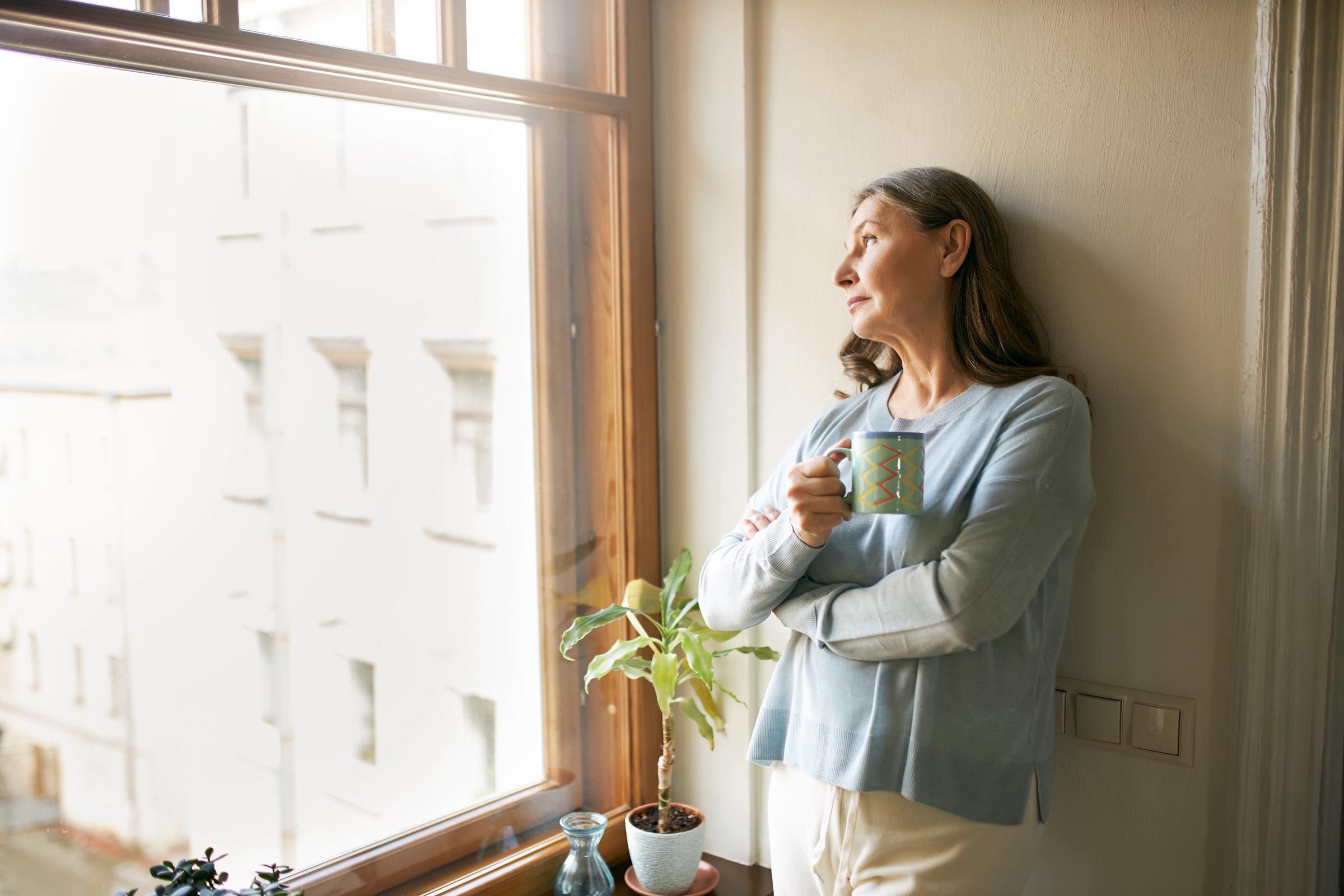 An elderly woman by the window | Source: Freepik