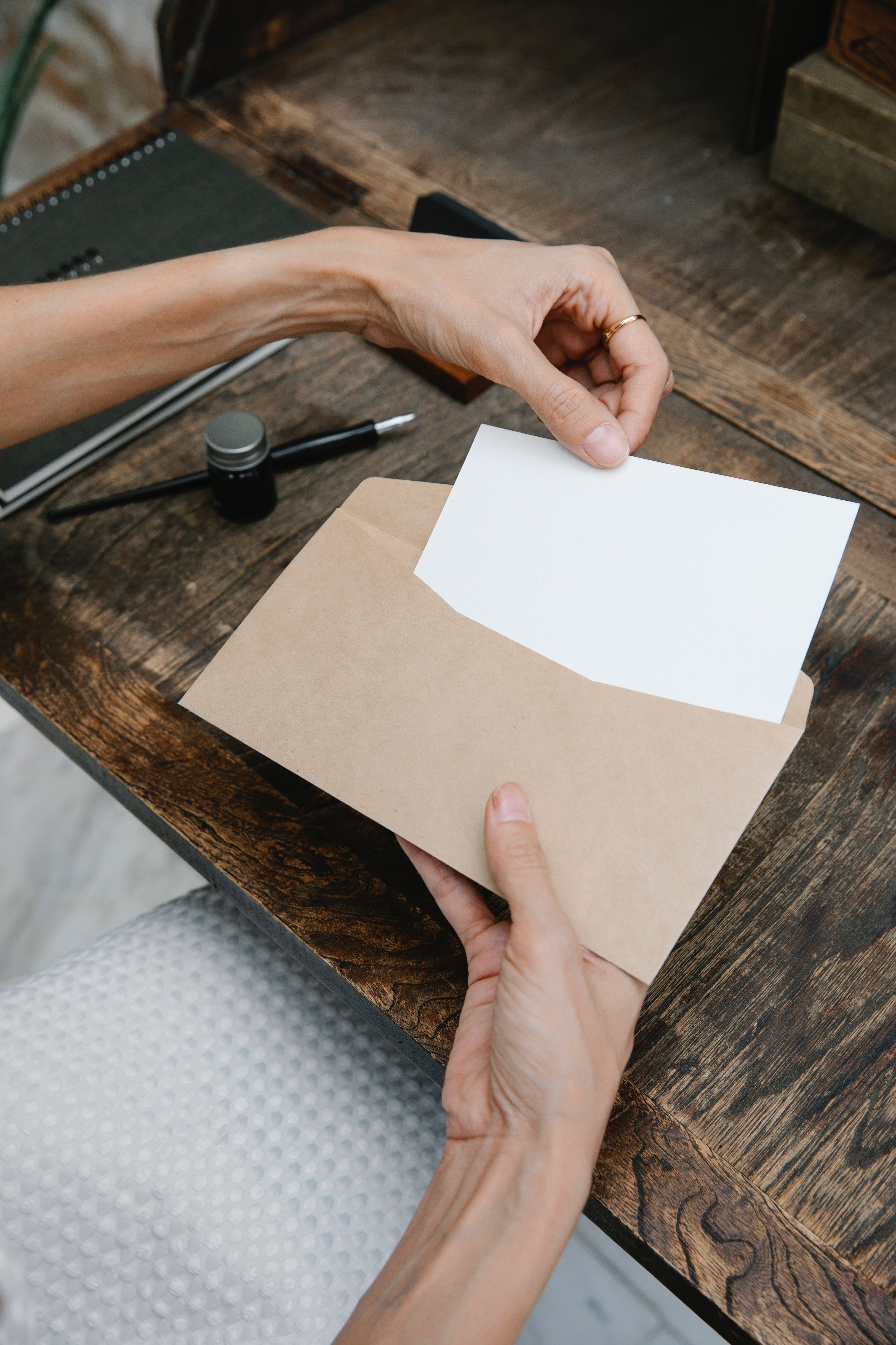 A woman placing a blank paper in an envelope | Source: Pexels