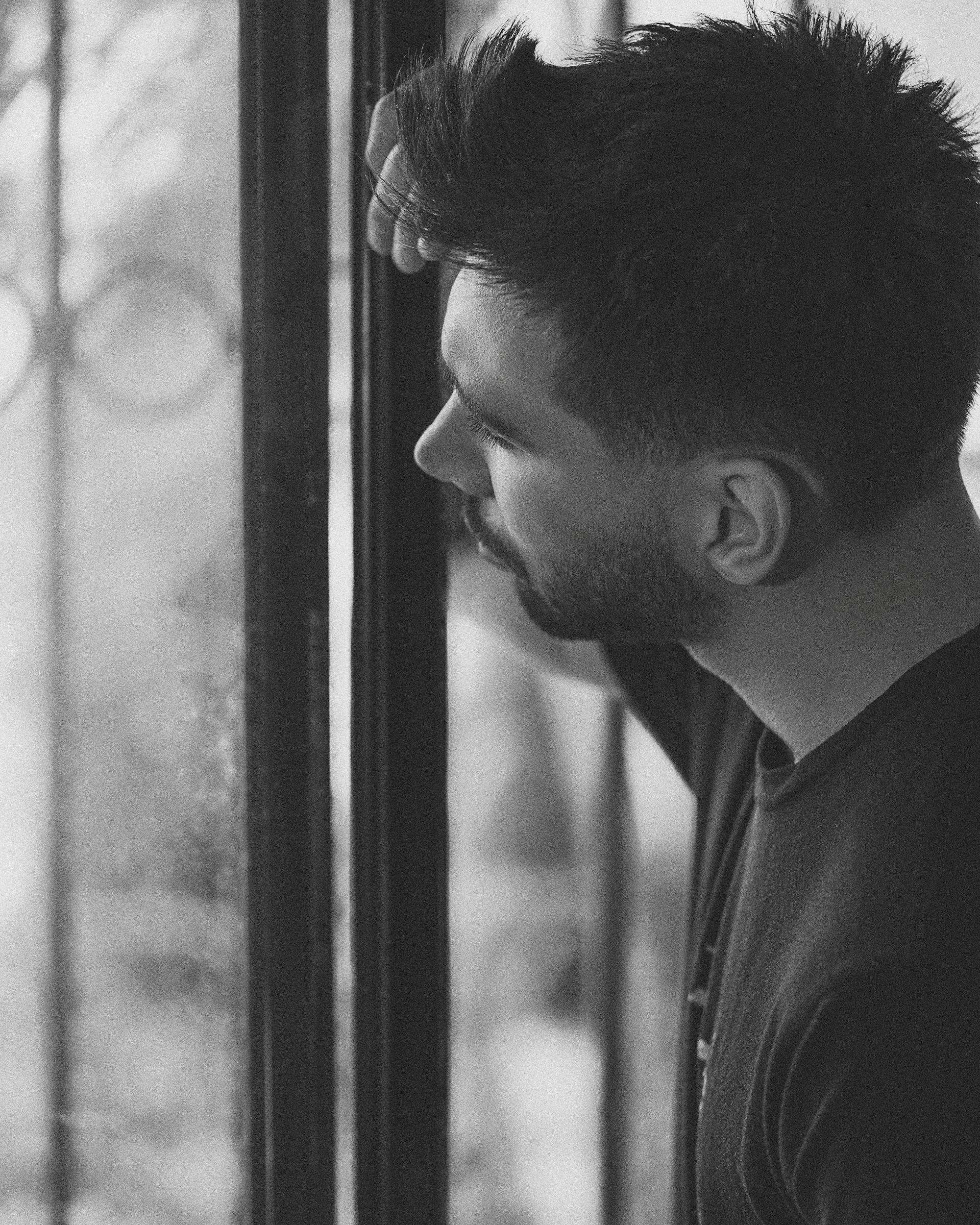 A grayscale photo of a man looking out the window | Source: Pexels