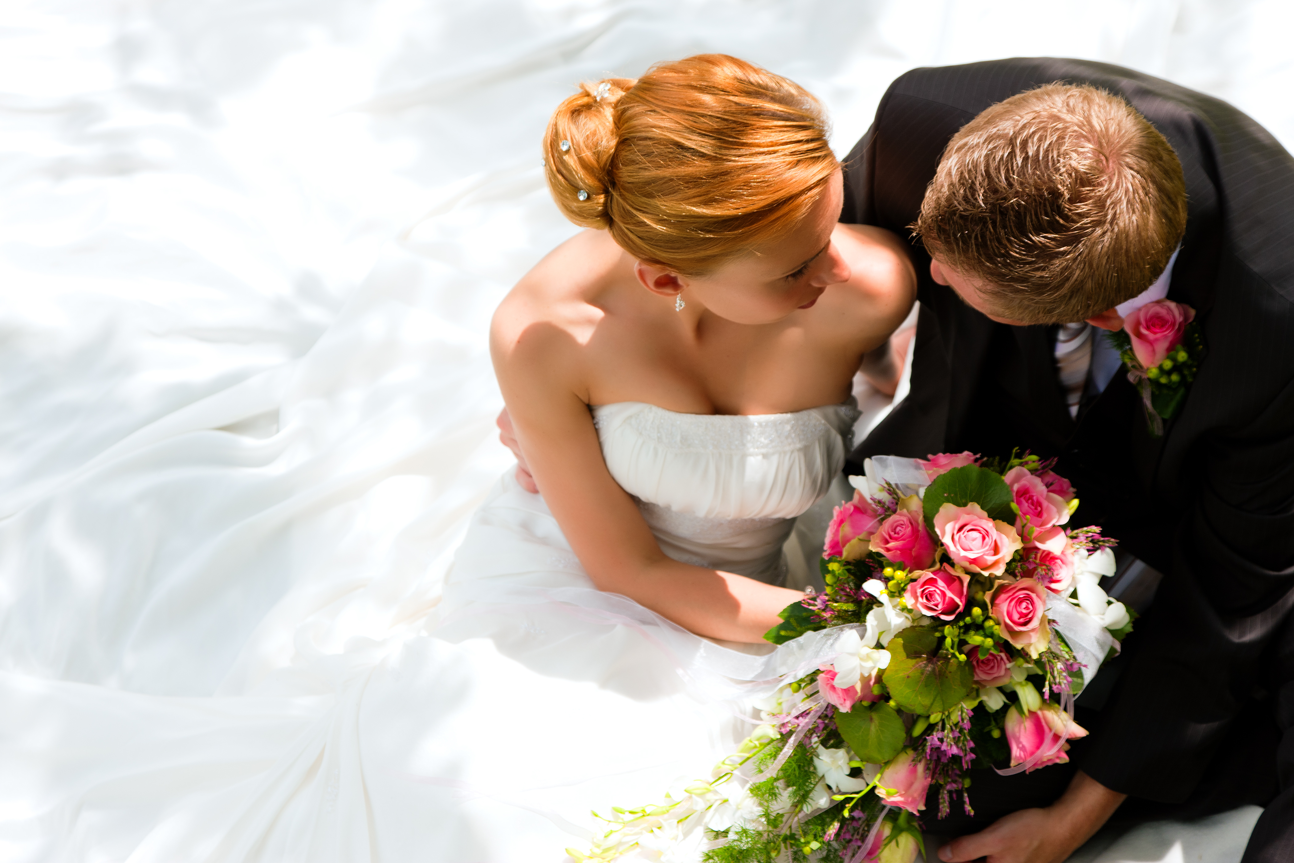 A groom holding a flower bouquet is pictured sitting beside his bride | Source: Shutterstock