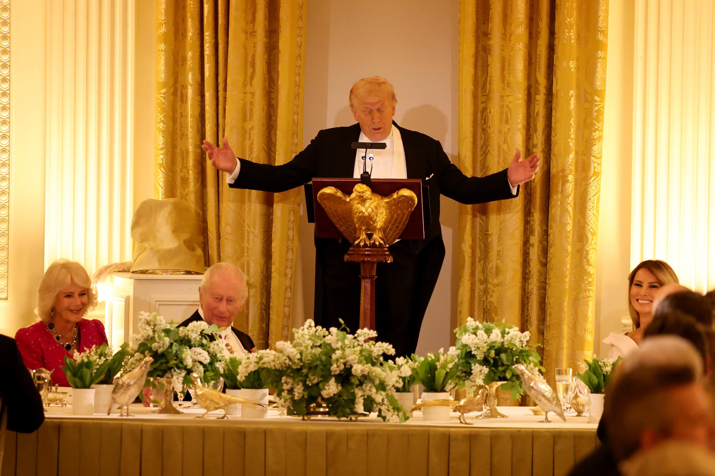 Donald Trump delivers remarks with both hands outstretched during a State Dinner in the White House East Room, April 28, 2026. | Source: Getty Images