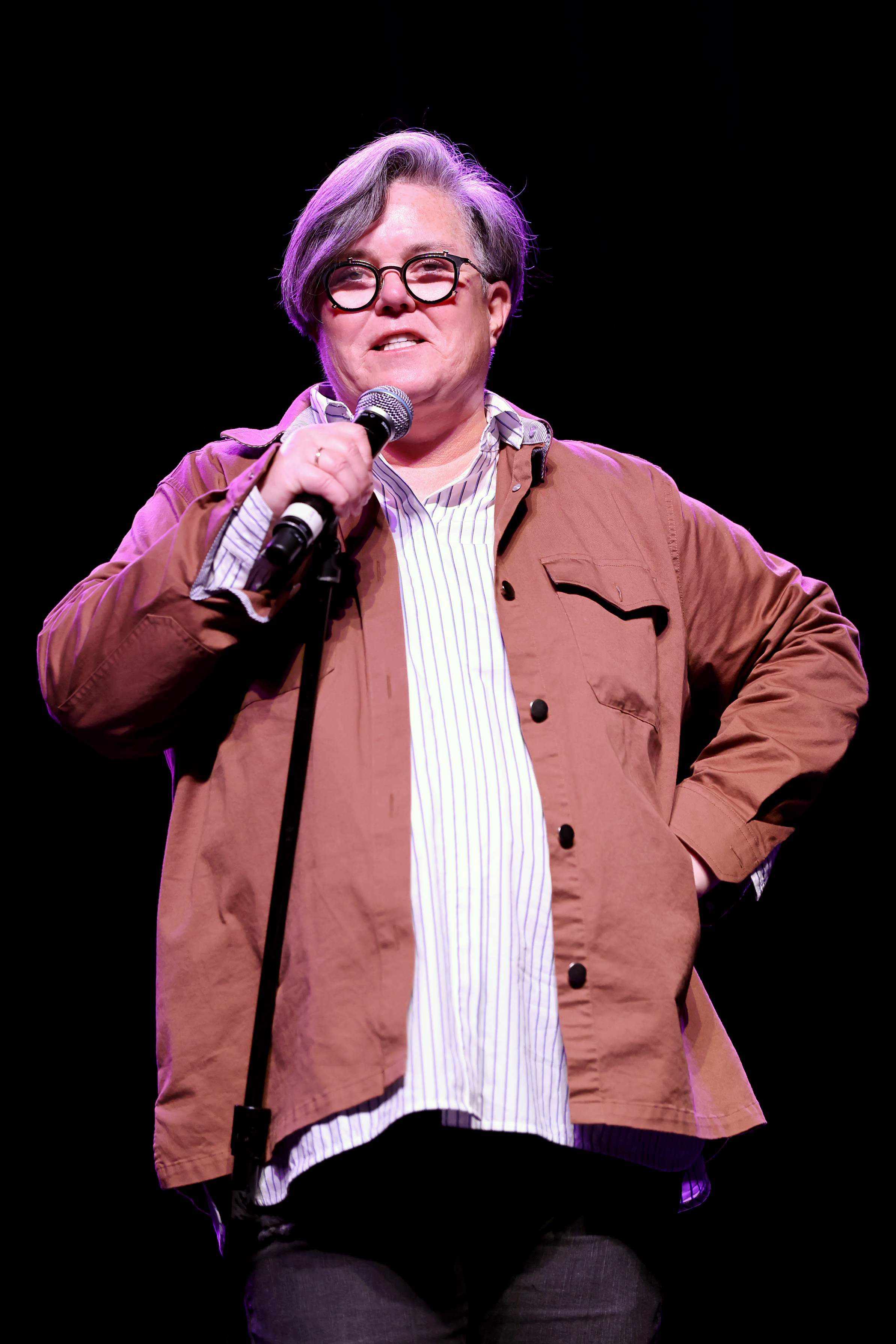 Mid-sentence and fully in her element, Rosie O'Donnell speaks to the crowd at the Friendly House LA Comedy Benefit on July 16, 2022. With focused eyes and a steady grip on the mic, she commands attention with quiet confidence.