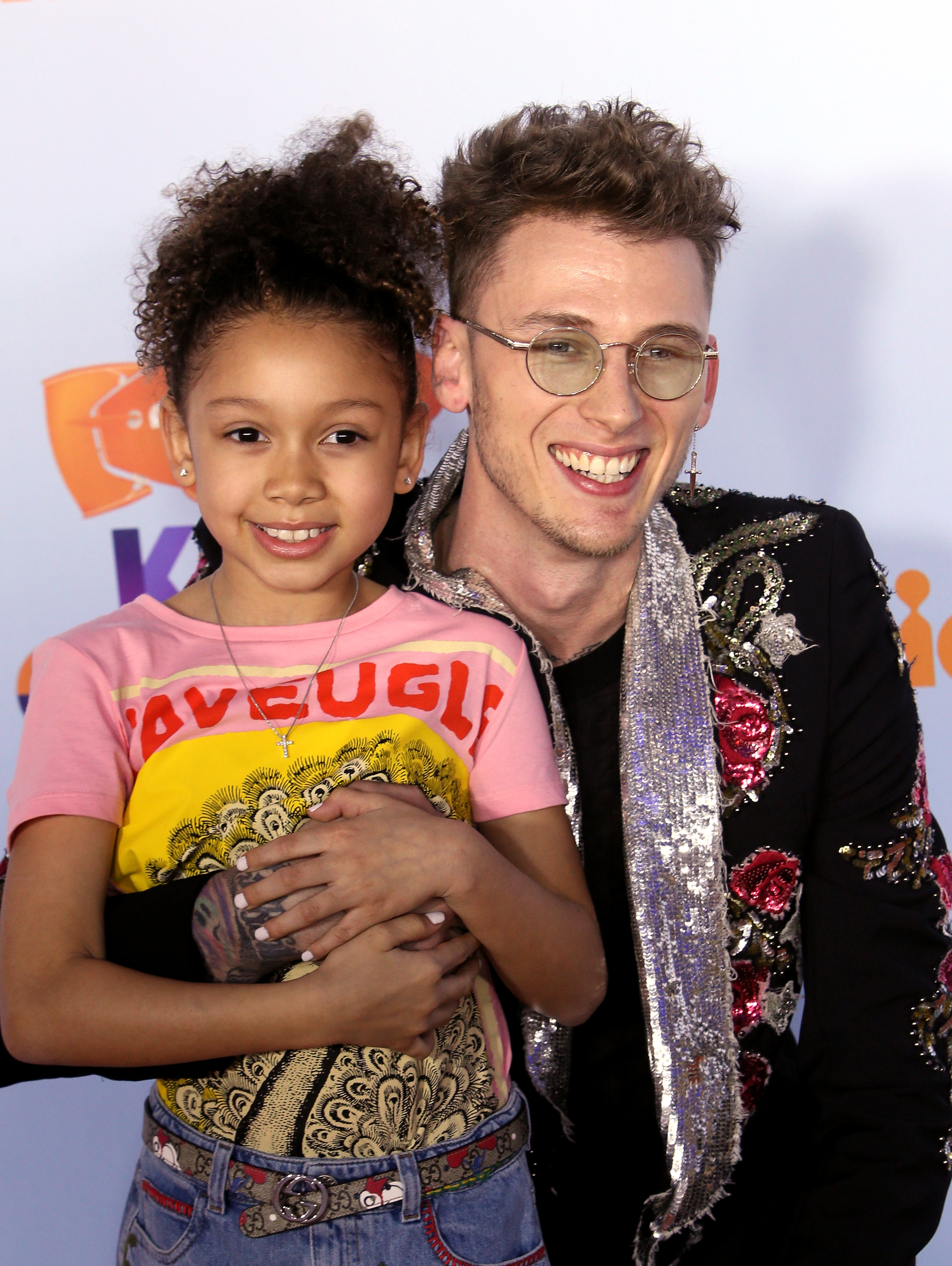 Machine Gun Kelly hugs a beaming young Casie Baker on the red carpet at the 2017 Kids' Choice Awards. She smiles with arms folded over his, capturing a sweet father-daughter moment.