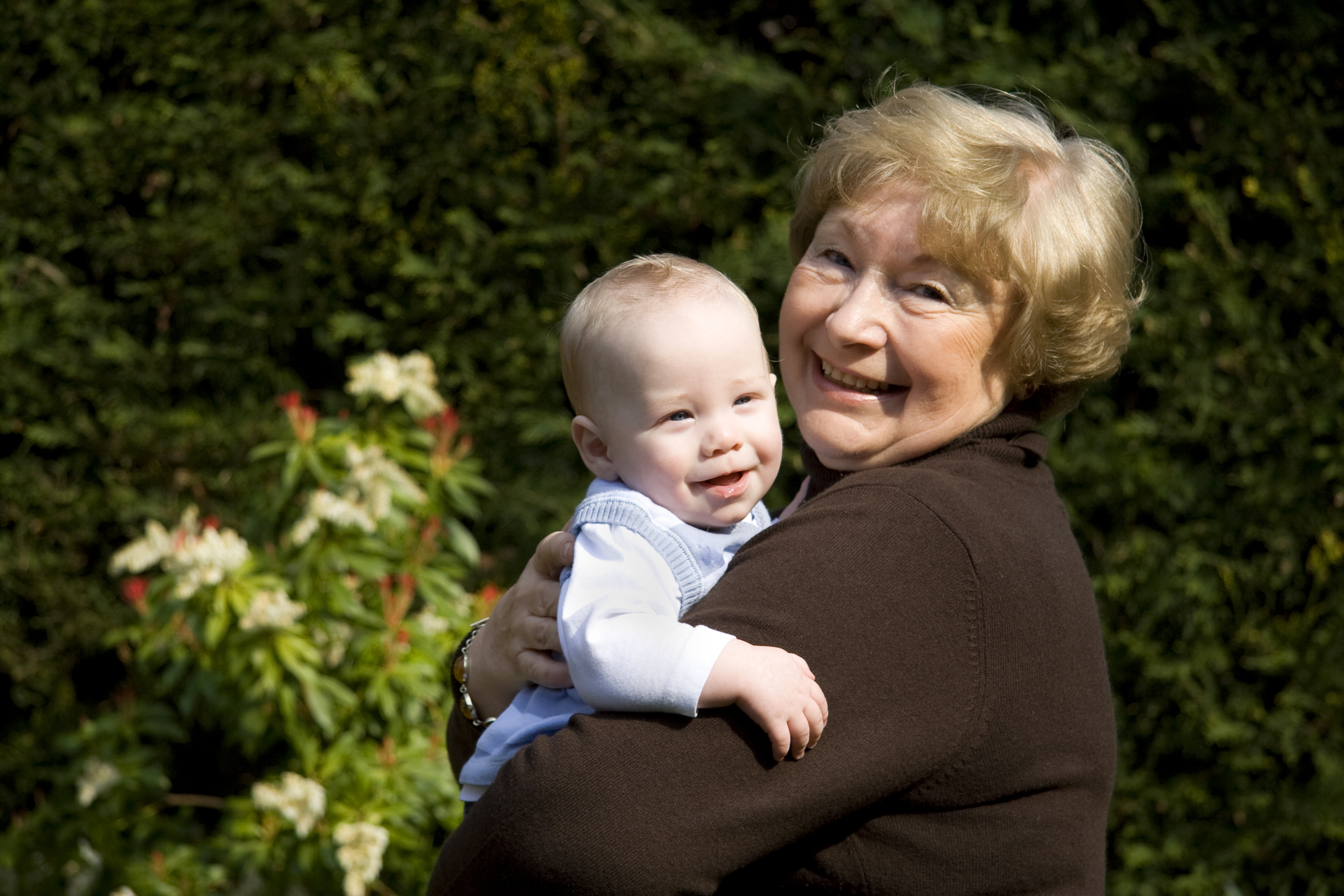 An older woman smiling while snuggling a happy baby | Source: Shutterstock