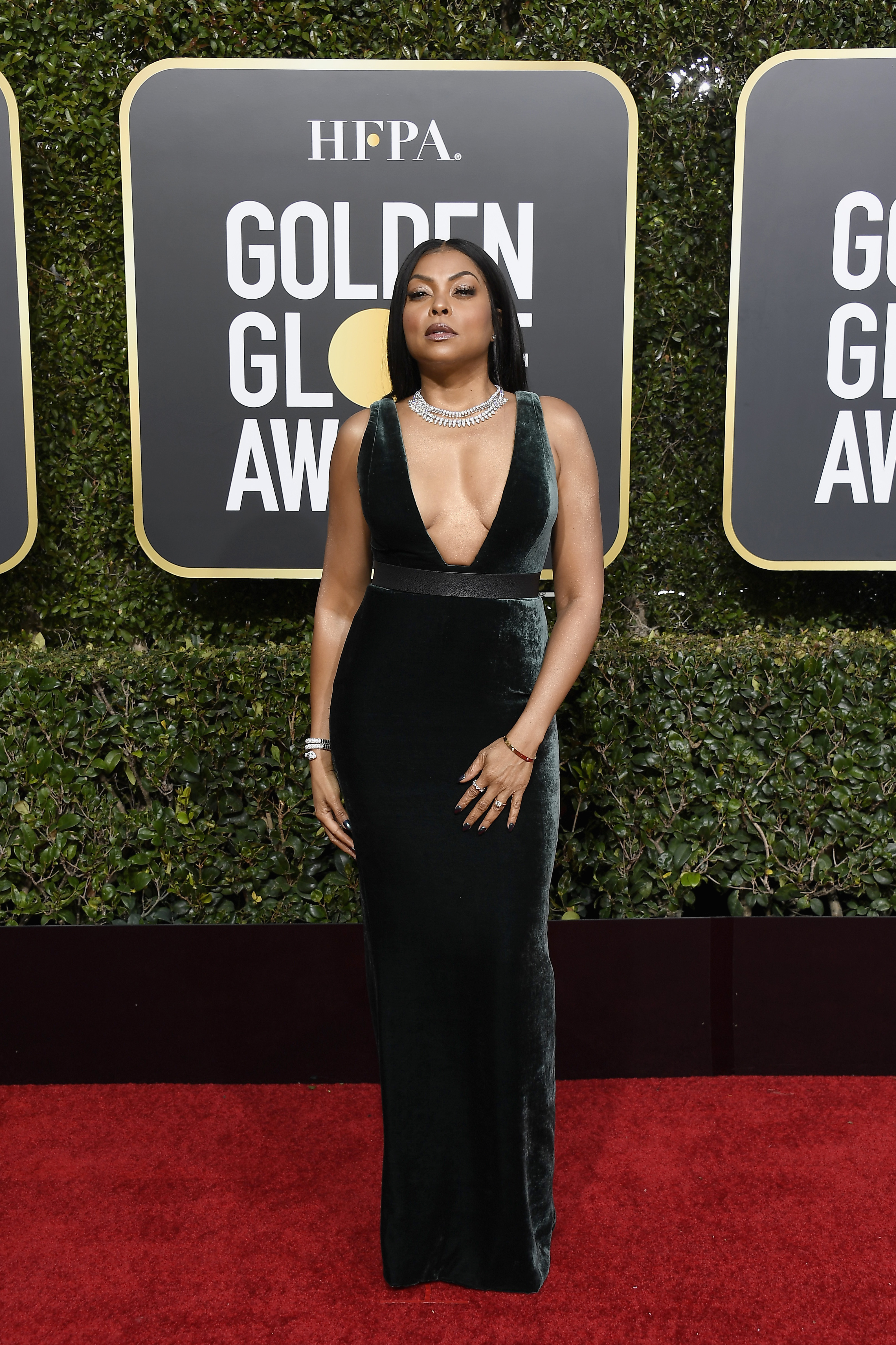 Taraji P. Henson arrives at the 76th Annual Golden Globe Awards at the Beverly Hilton Hotel in a sleeveless deep-green velvet gown with a plunging neckline and a defined waist band, standing tall with both arms relaxed at her sides as she faces forward on the red carpet.