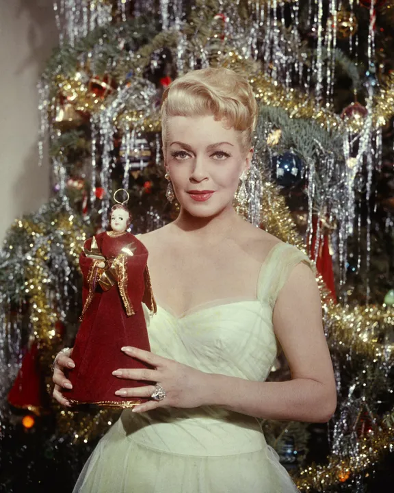 L'actrice américaine Lana Turner (1921 - 1995) tenant l'ange du haut d'un arbre de Noël, vers 1965.| Source : Getty Images