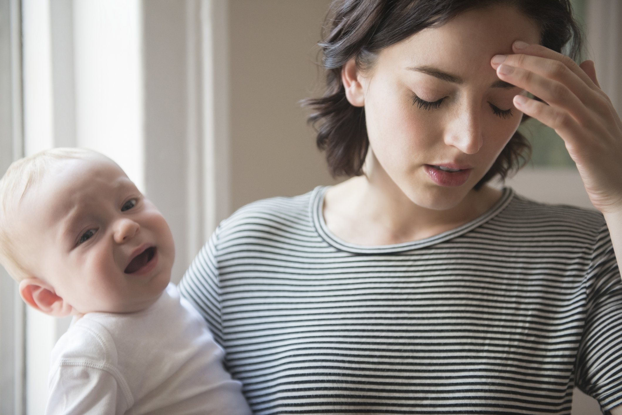 Mutter reibt sich die Stirn, während sie den kleinen Sohn hält. I Quelle: Getty Images