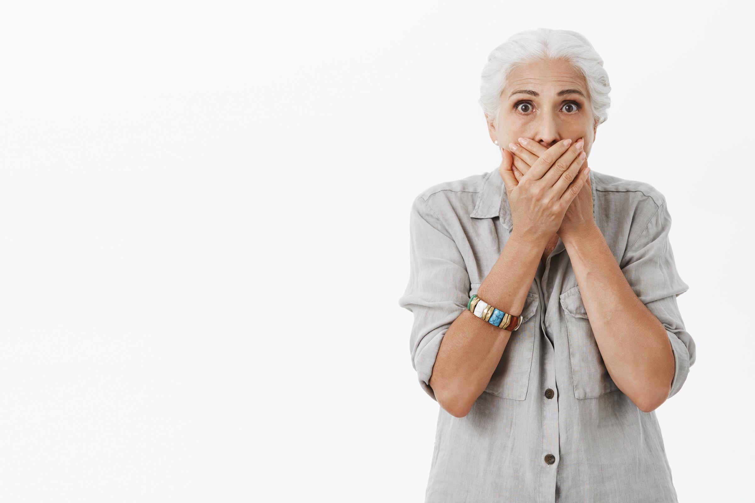 A startled senior woman covering her mouth | Source: Freepik