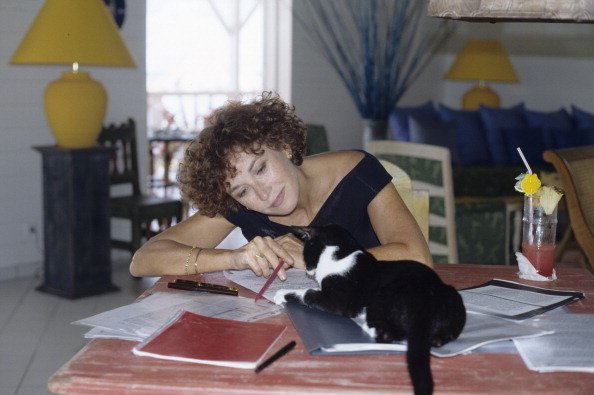Jobert Marlene et ses jumeaux Eva et Joy en vacances dans les Antilles françaises. Au domaine de LONVILLIERS, Marlène JOBERT, écrivant en intérieur, en compagnie de son chat. | Photo : Getty Images