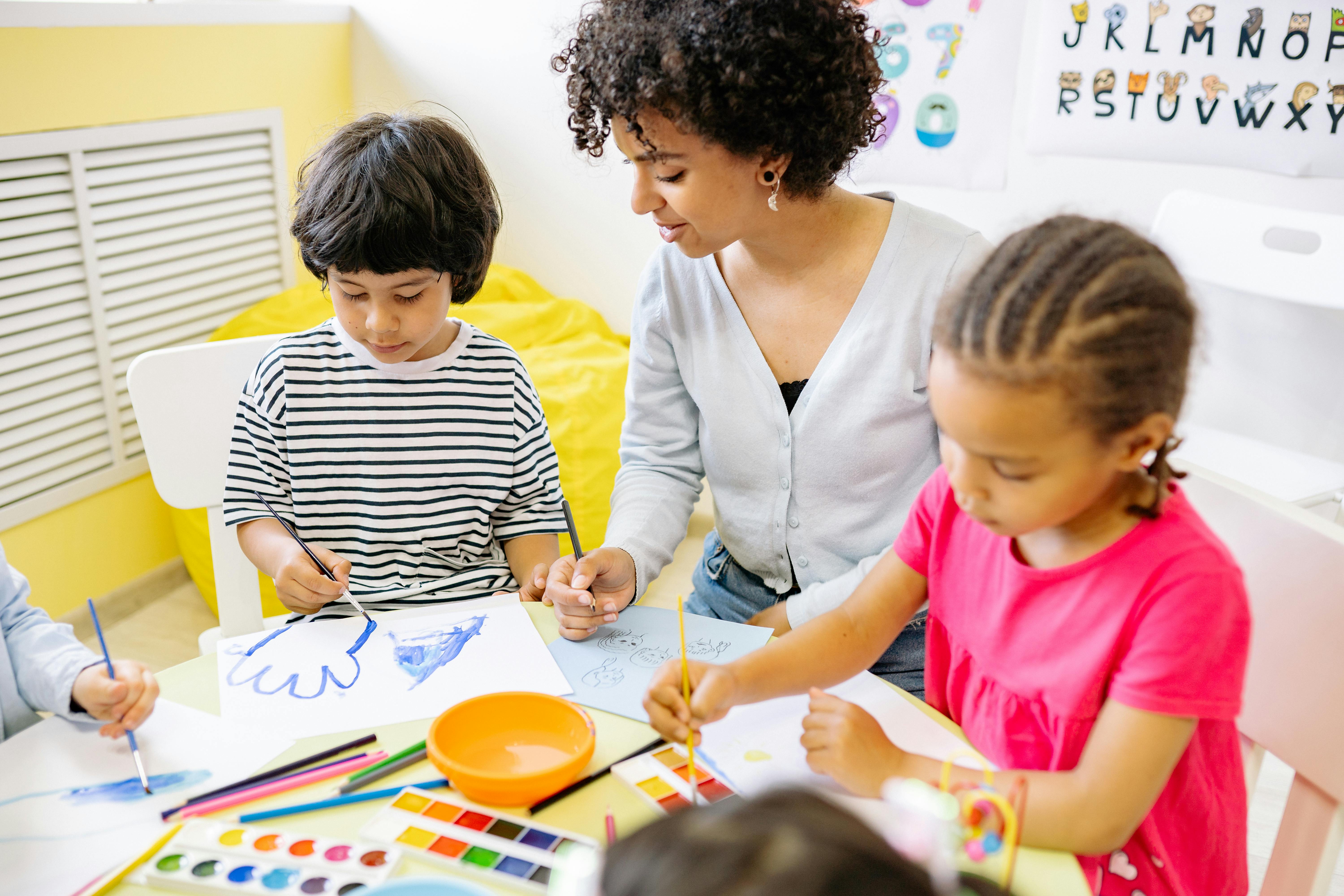 A woman painting alongside two children | Source: Pexels