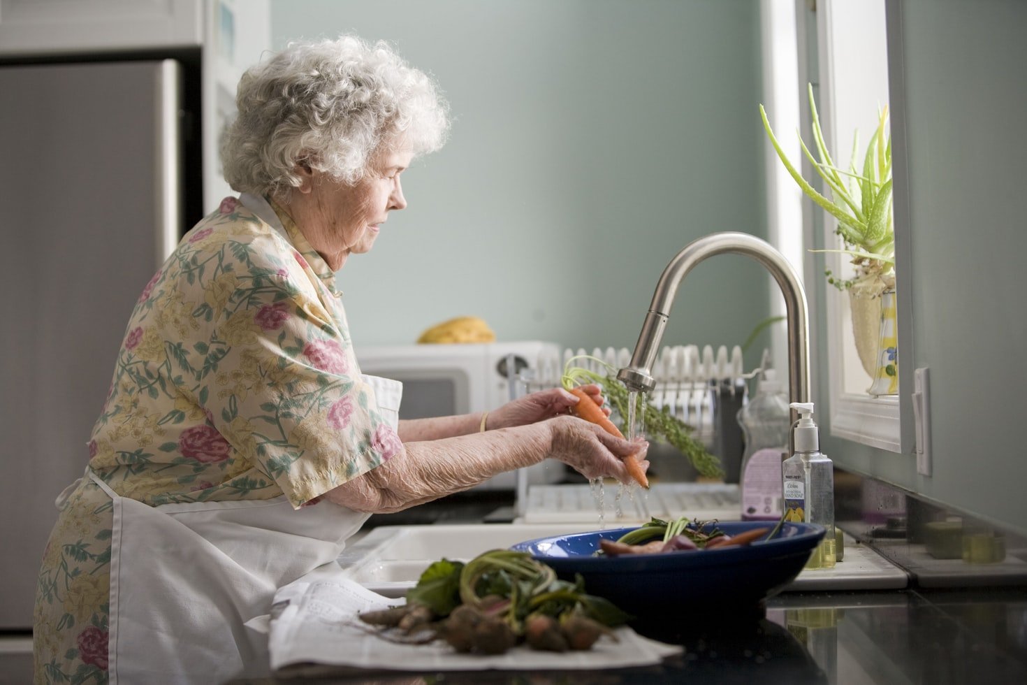 Una abuela lavando vegetales. | Foto: Unsplash