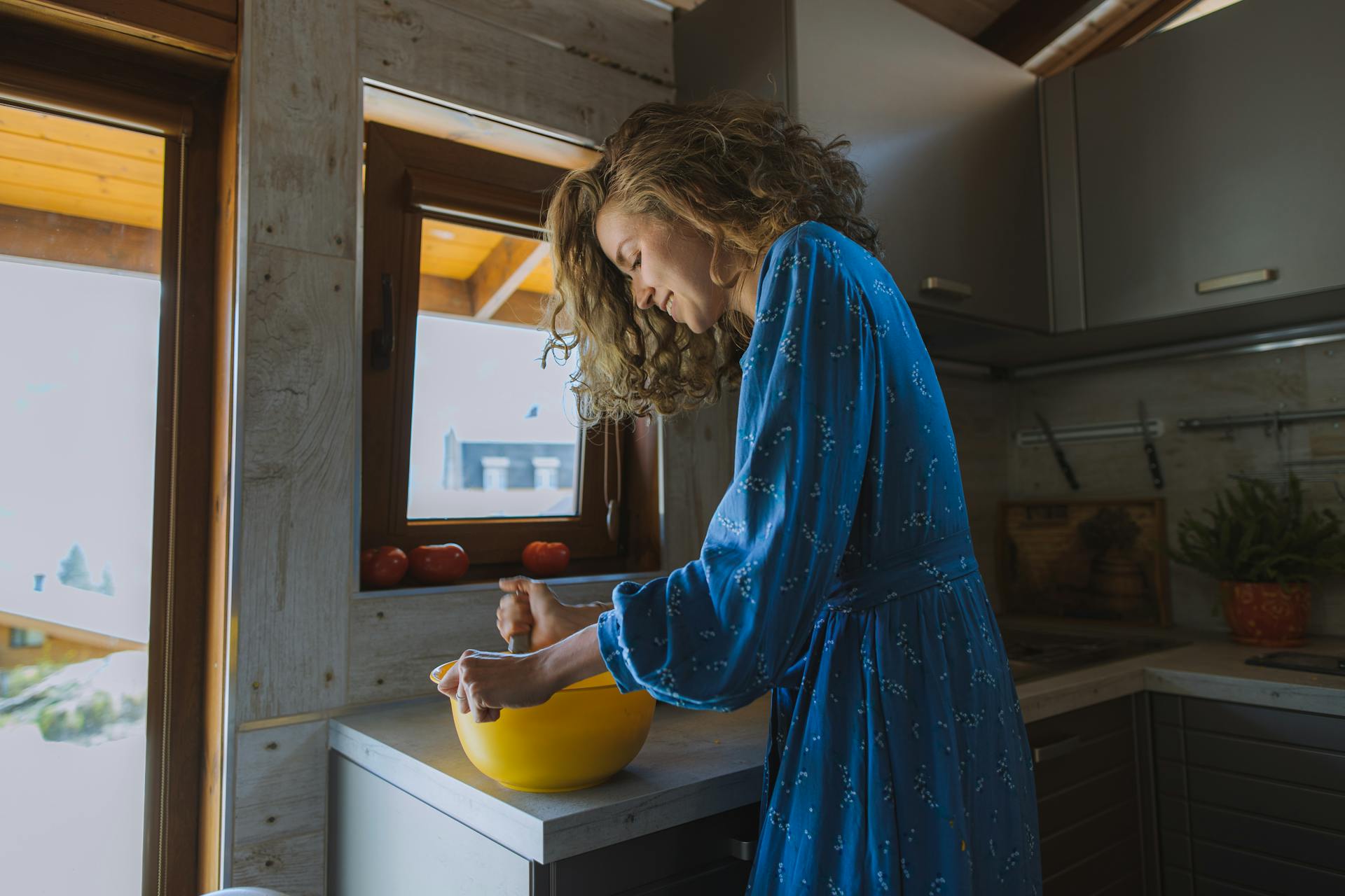 A smiling woman holding a yellow ball in a kitchen | Source: Pexels