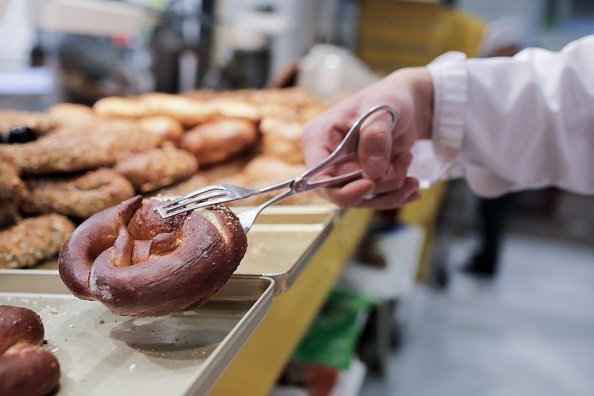 A baker takes a lye pretzel with a forceps from the display | Photo: Getty Images