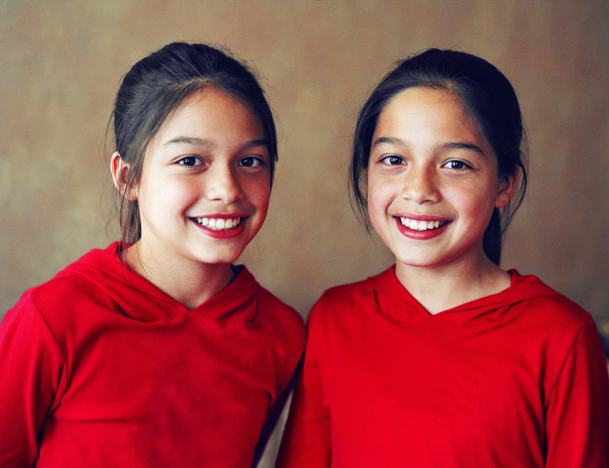 Zwillingsmädchen lächeln, während sie für ein Foto posieren. | Quelle: Getty Images