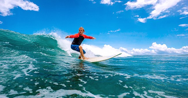 A teenager surfing in the ocean | Photo: Shutterstock