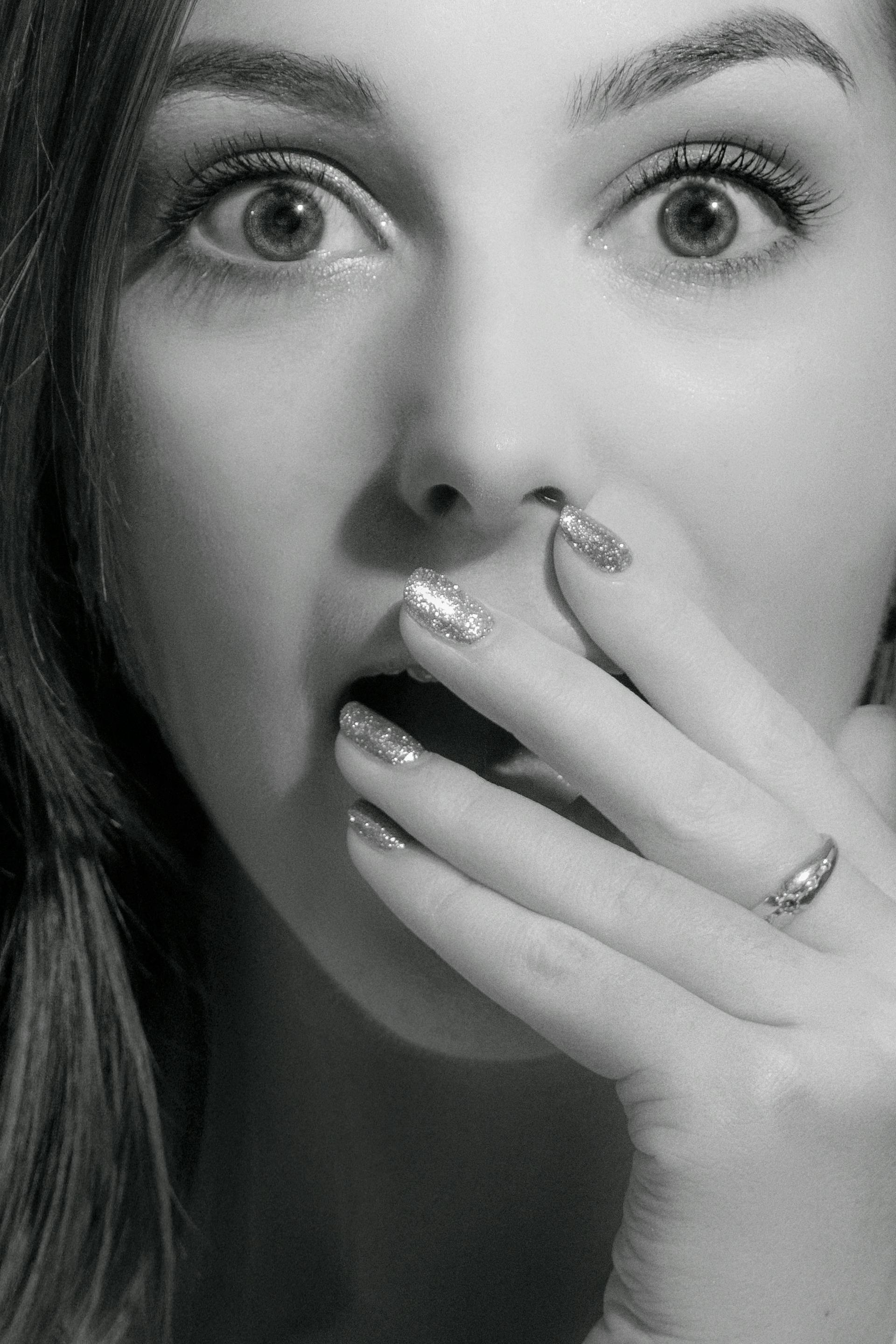 Close-up grayscale shot of a shocked woman covering her mouth | Source: Pexels