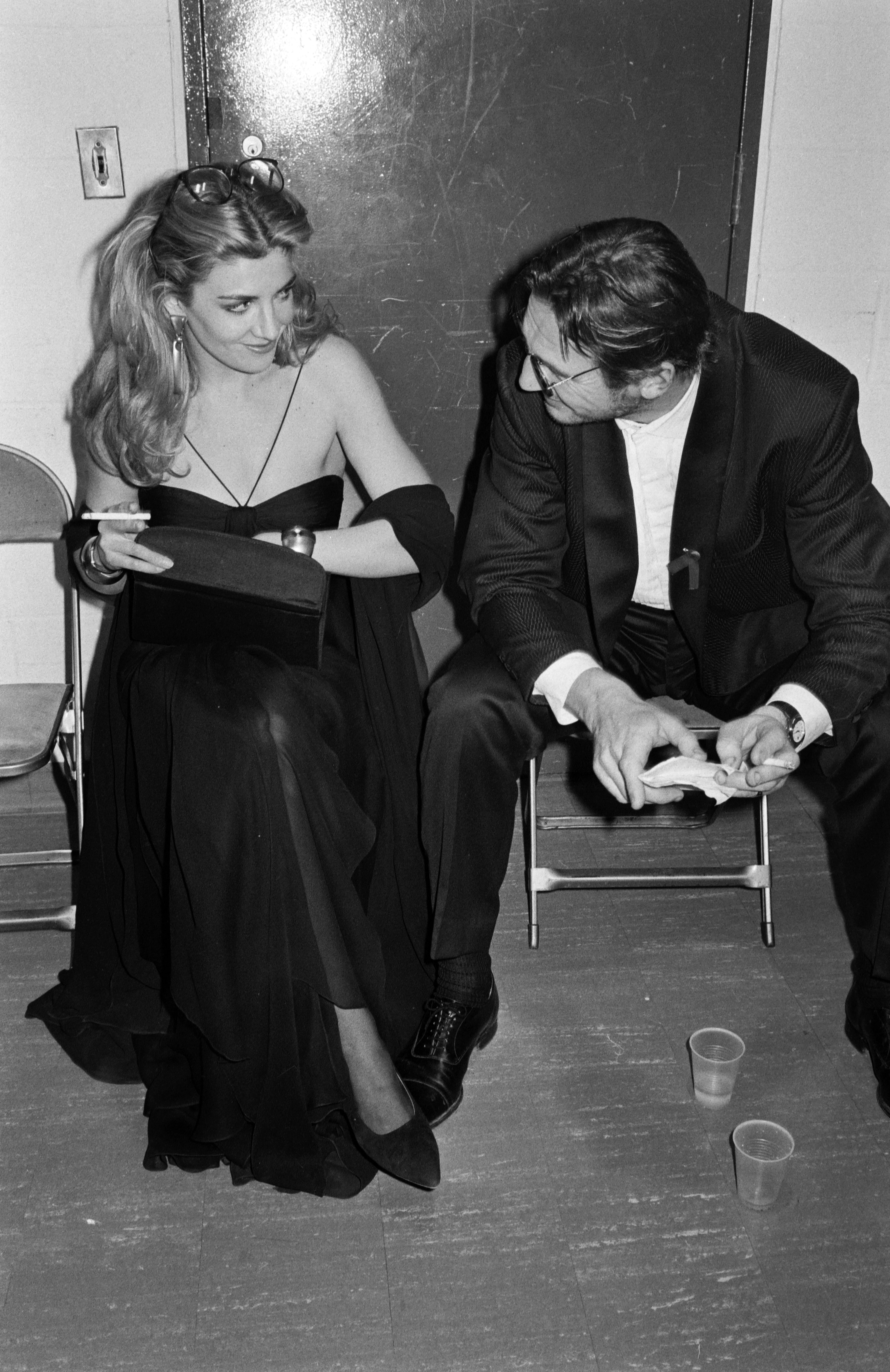 Natasha Richardson and Liam Neeson sit side by side backstage at the CFDA Fashion Awards in New York City on February 2, 1993. They appear engaged in a lighthearted conversation, sharing a quiet moment away from the main event. Ask ChatGPT