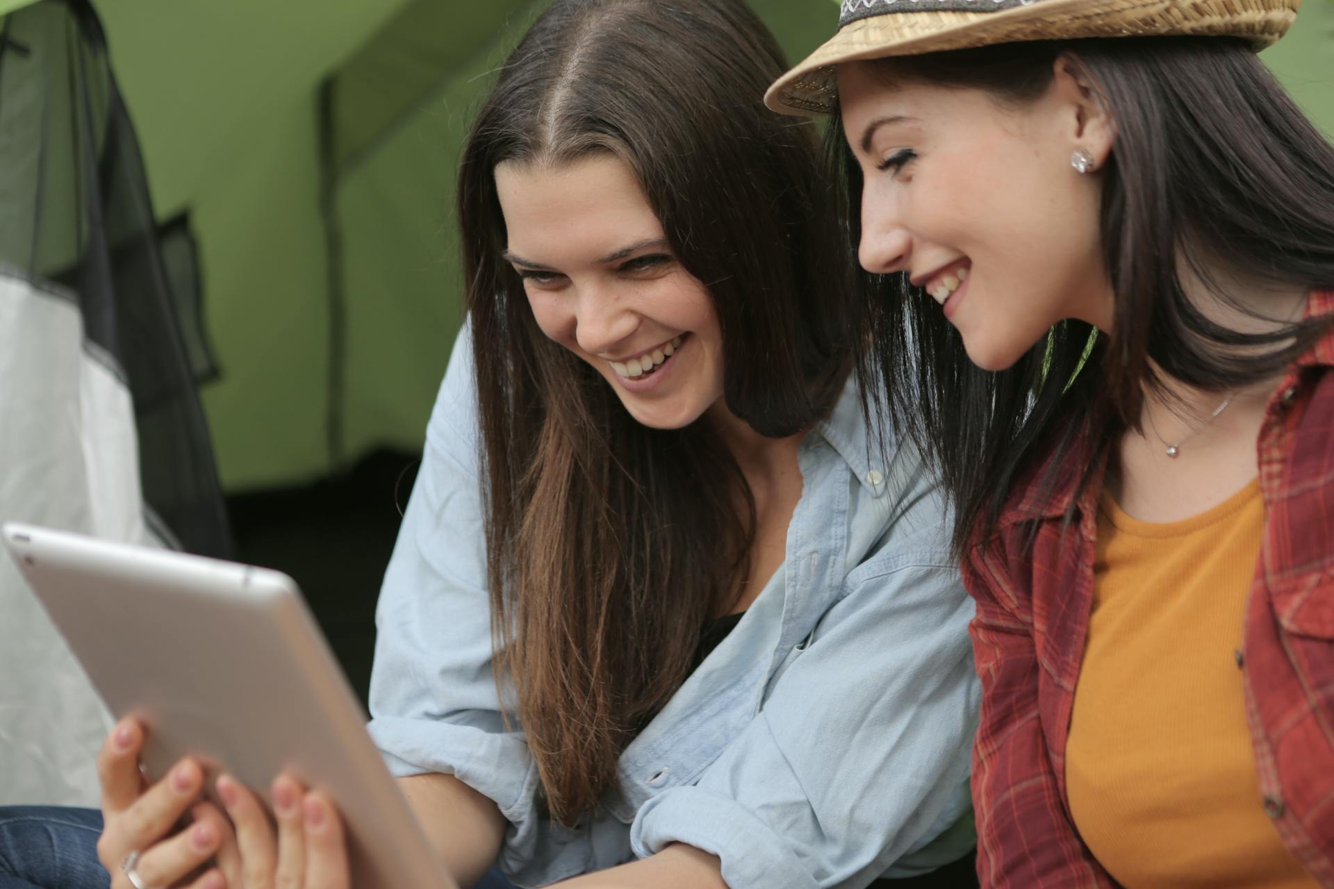 Two women smiling while looking at an iPad | Source: Pexels