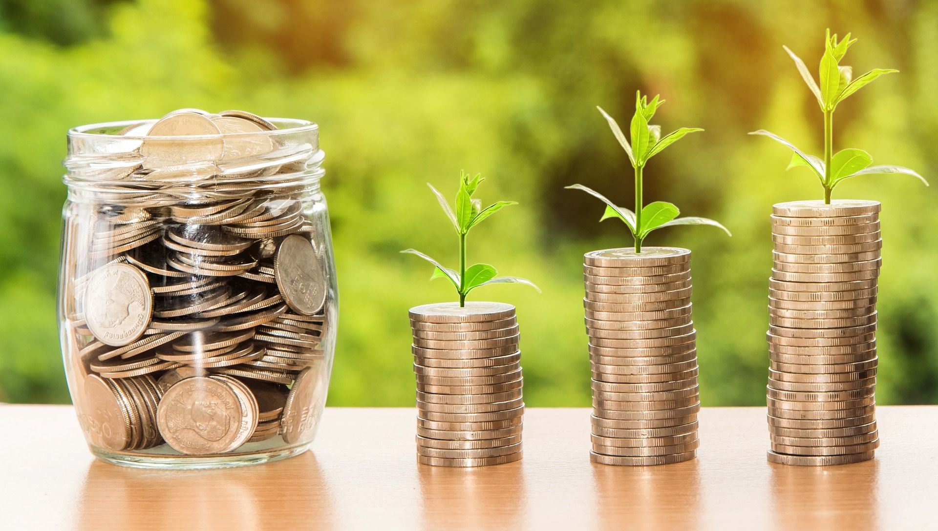 Coins in a jar next to stacked up coins with small plants sprouting out of them. | Source: Shutterstock