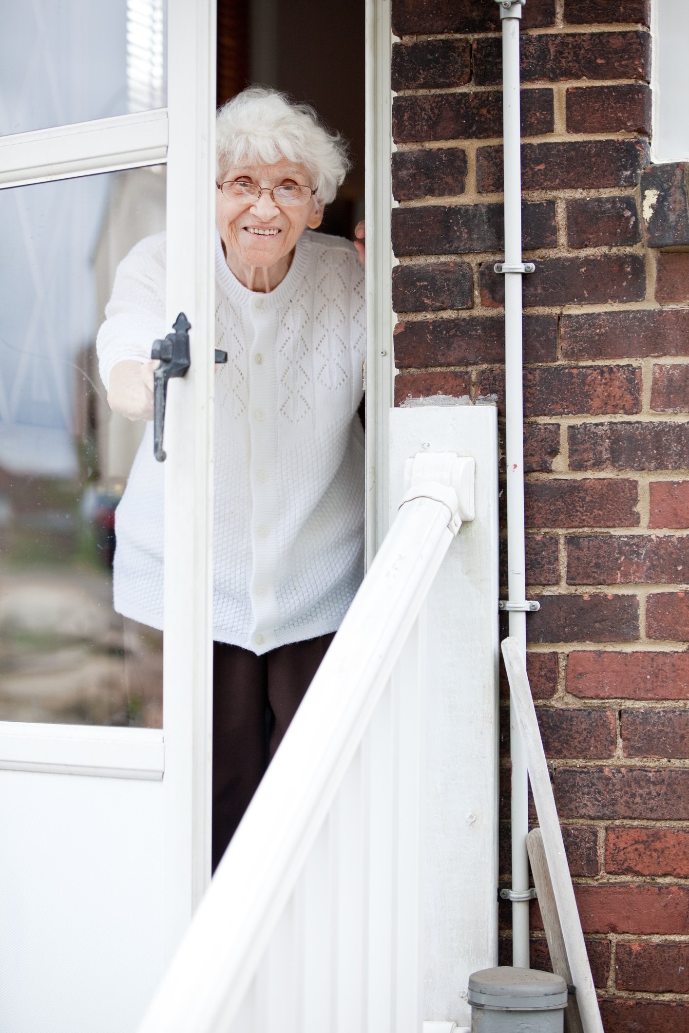 Una anciana sonriente abre la puerta de su hogar. | Foto: Getty Images