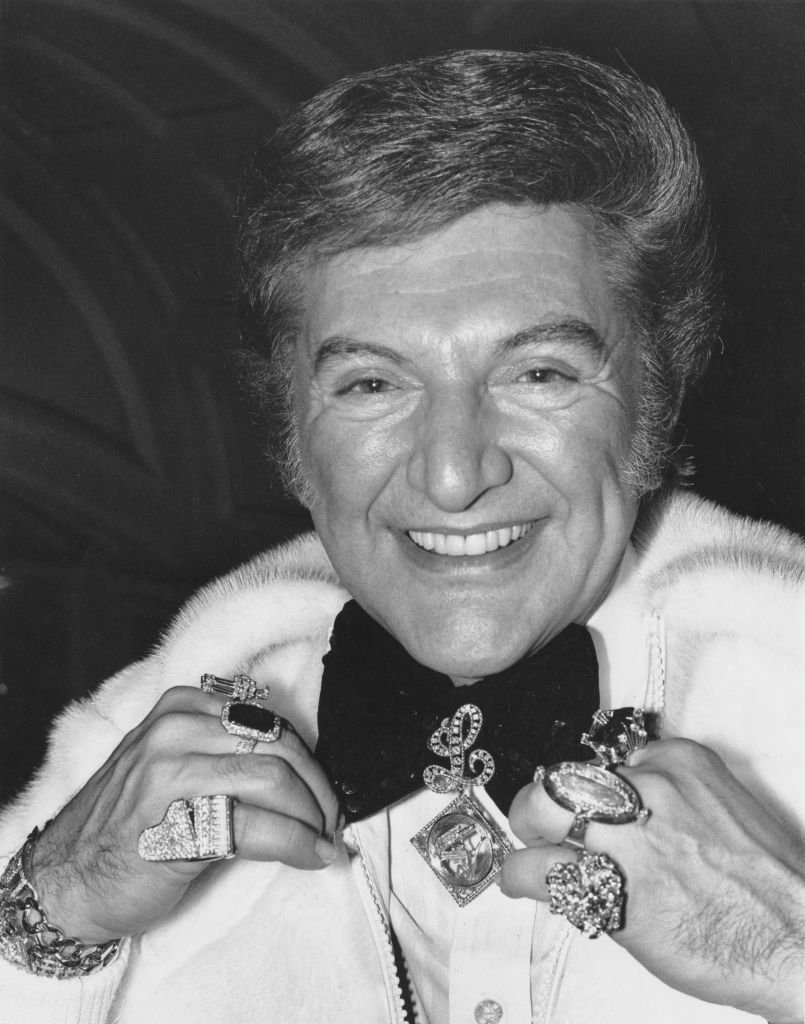 Liberace, born Wladziu Valentino Liberace (1919 - 1987), showing off some of his jewellery upon his arrival in London | Getty Images