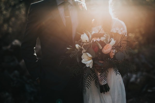 Groom standing beside bride holding flowers | Source: Unsplash