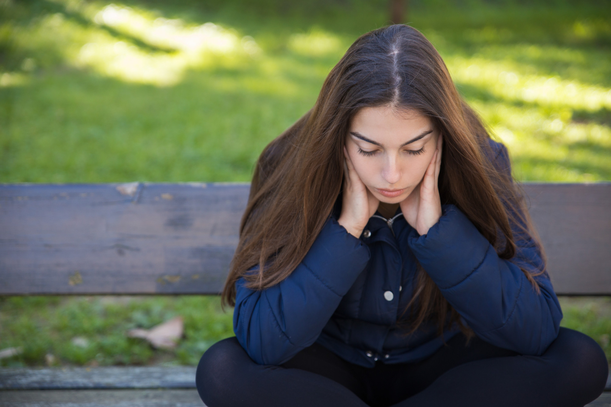 A pensive young woman sitting on a bench in a park | Source: Freepik