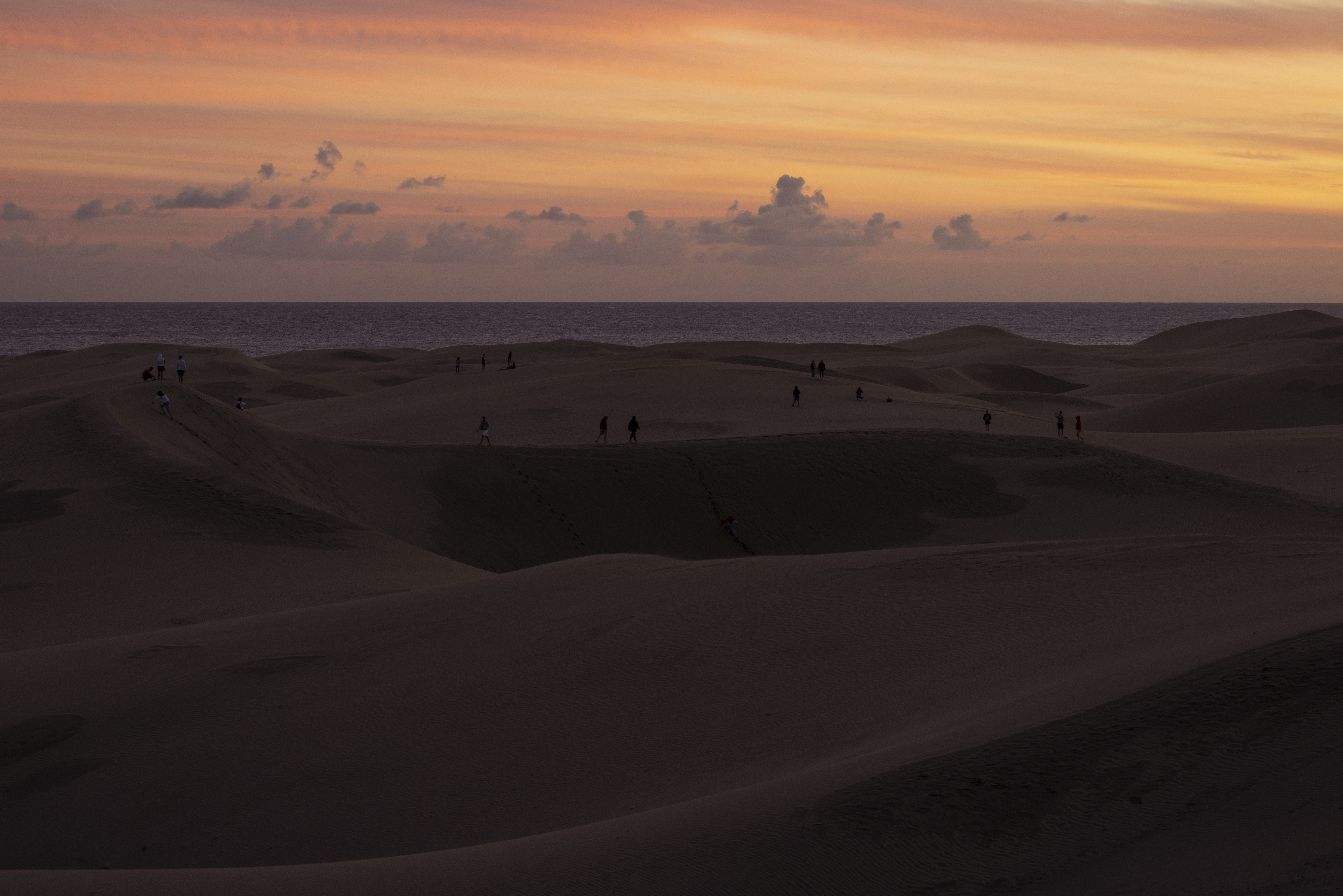 People walk through the sand dunes at sunset on December 7, 2020, in Maspalomas, Spain. | Source: Getty Images