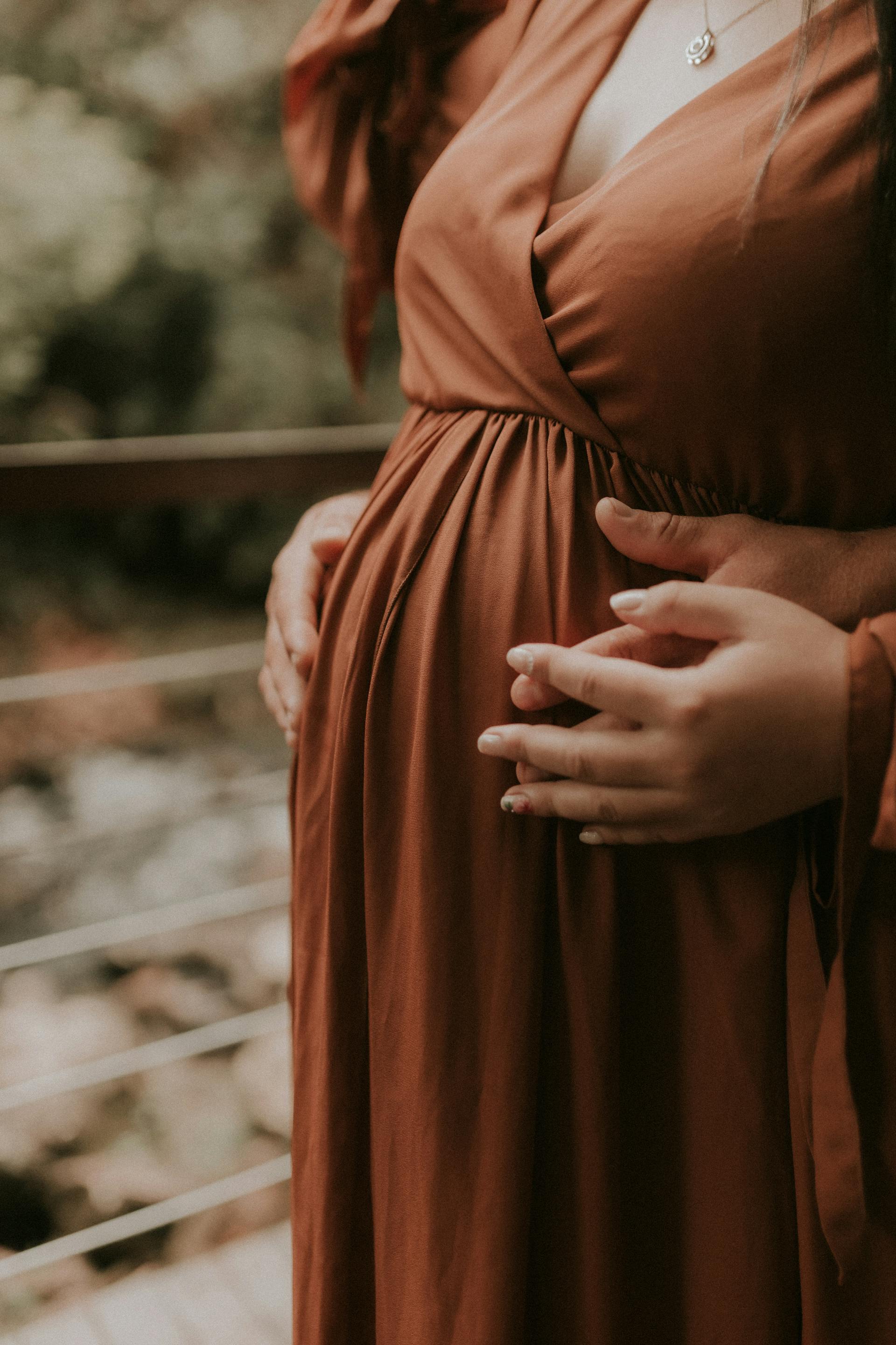 A couple holding hands while touching the pregnant woman's baby bump | Source: Pexels