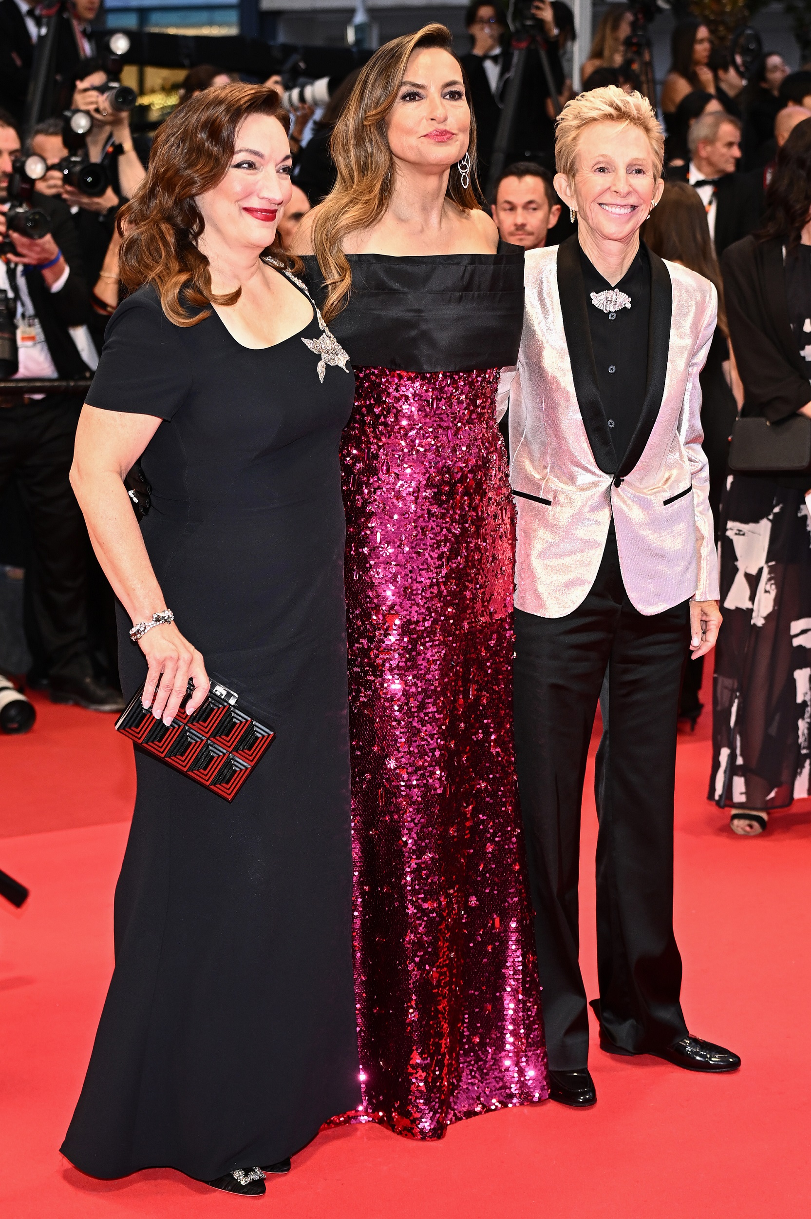 Mariska and Trish are joined by Lauran Bromley, another producer on "My Mom Jayne". Bromley wears a white metallic blazer with black lapels over a black shirt and trousers, adding a striking, tailored edge to the trio's red carpet presence.