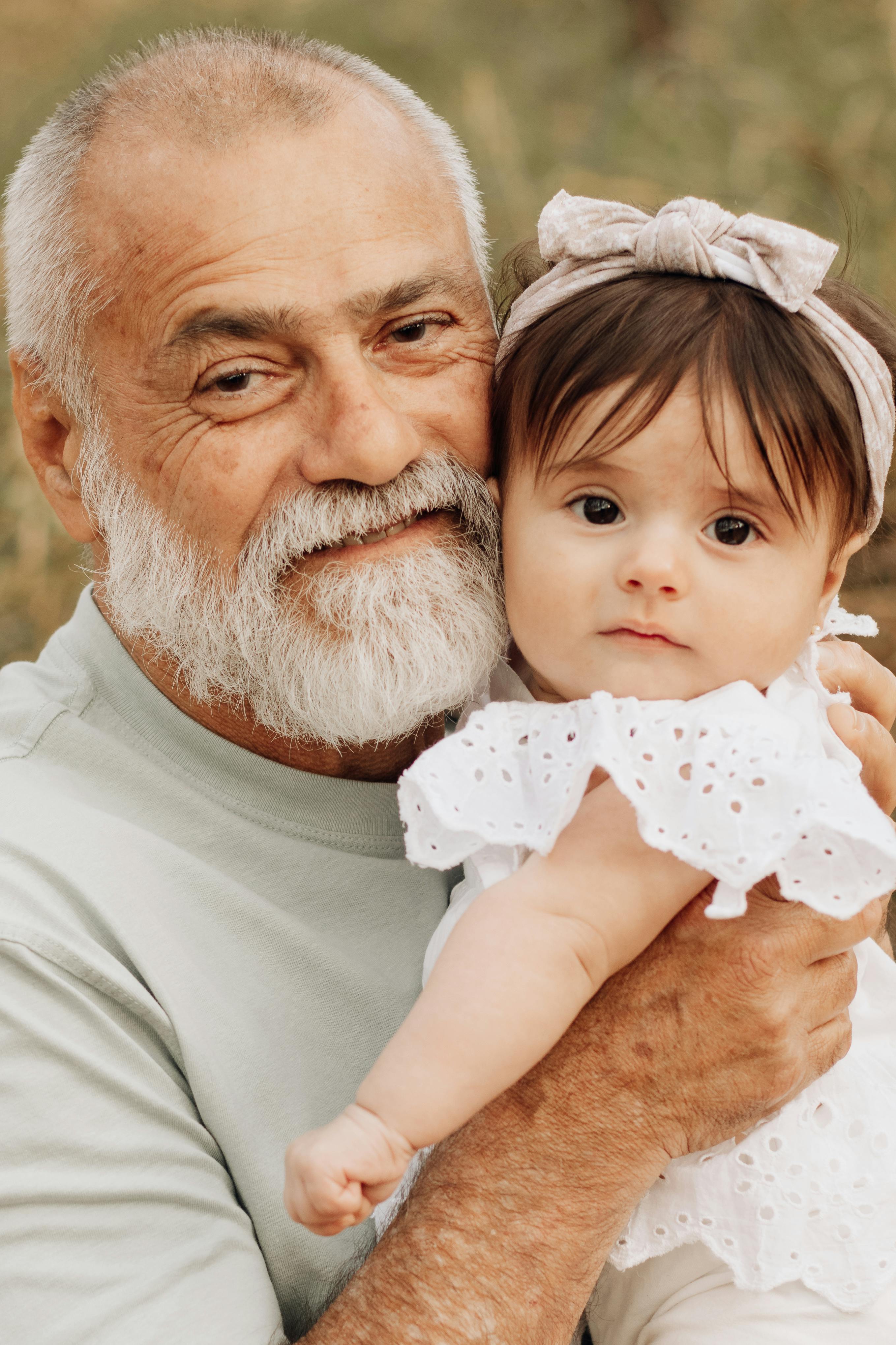 An older man holding a girl child | Source: Pexels