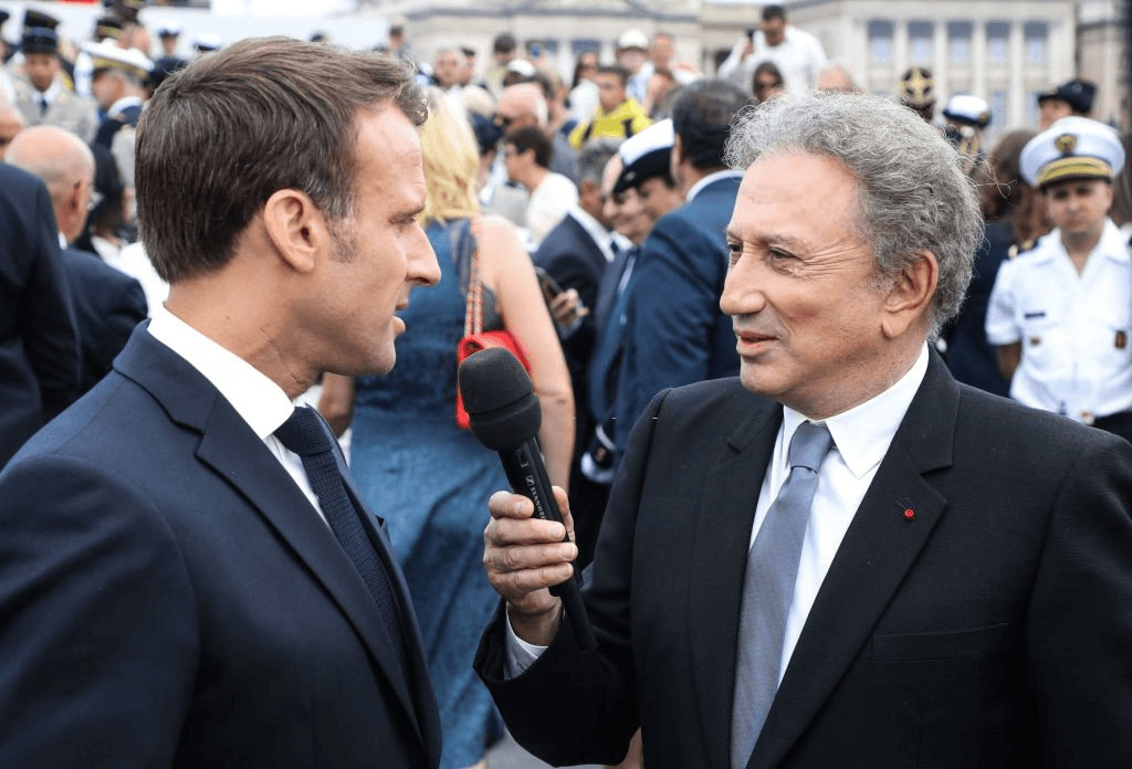 Le président français Emmanuel Macron (à gauche) répond aux questions de l'animateur Michel Drucker à la fin du défilé militaire annuel du 14 juillet 2019 sur l'avenue Champs-Elysées à Paris. | Photo : Getty Images
