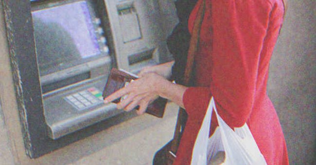 Mujer abriendo su billetera frente a un cajero automático. | Foto: Shutterstock