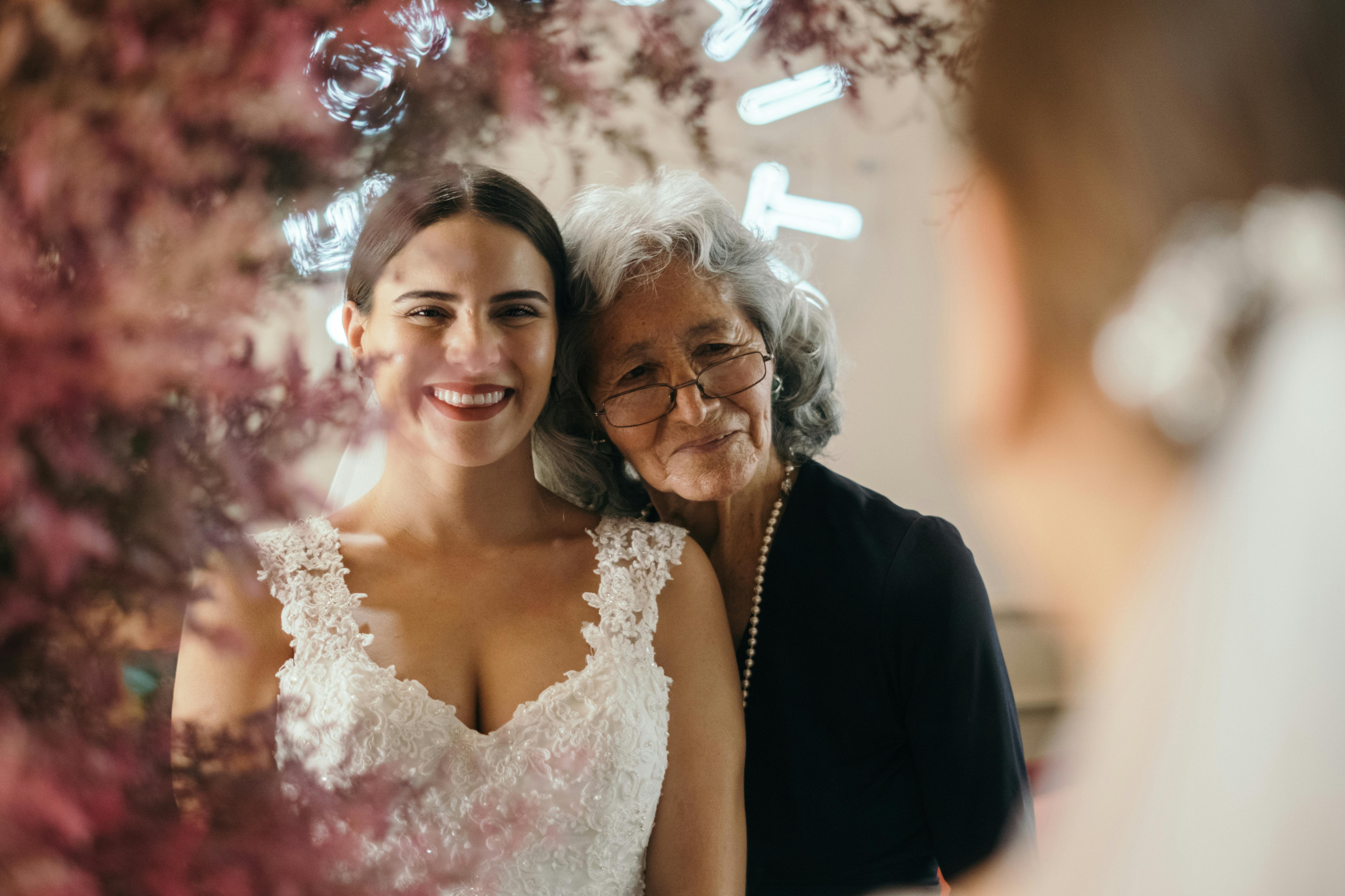 A bride and older woman inspect the fit of a wedding dress | Source: Pexels