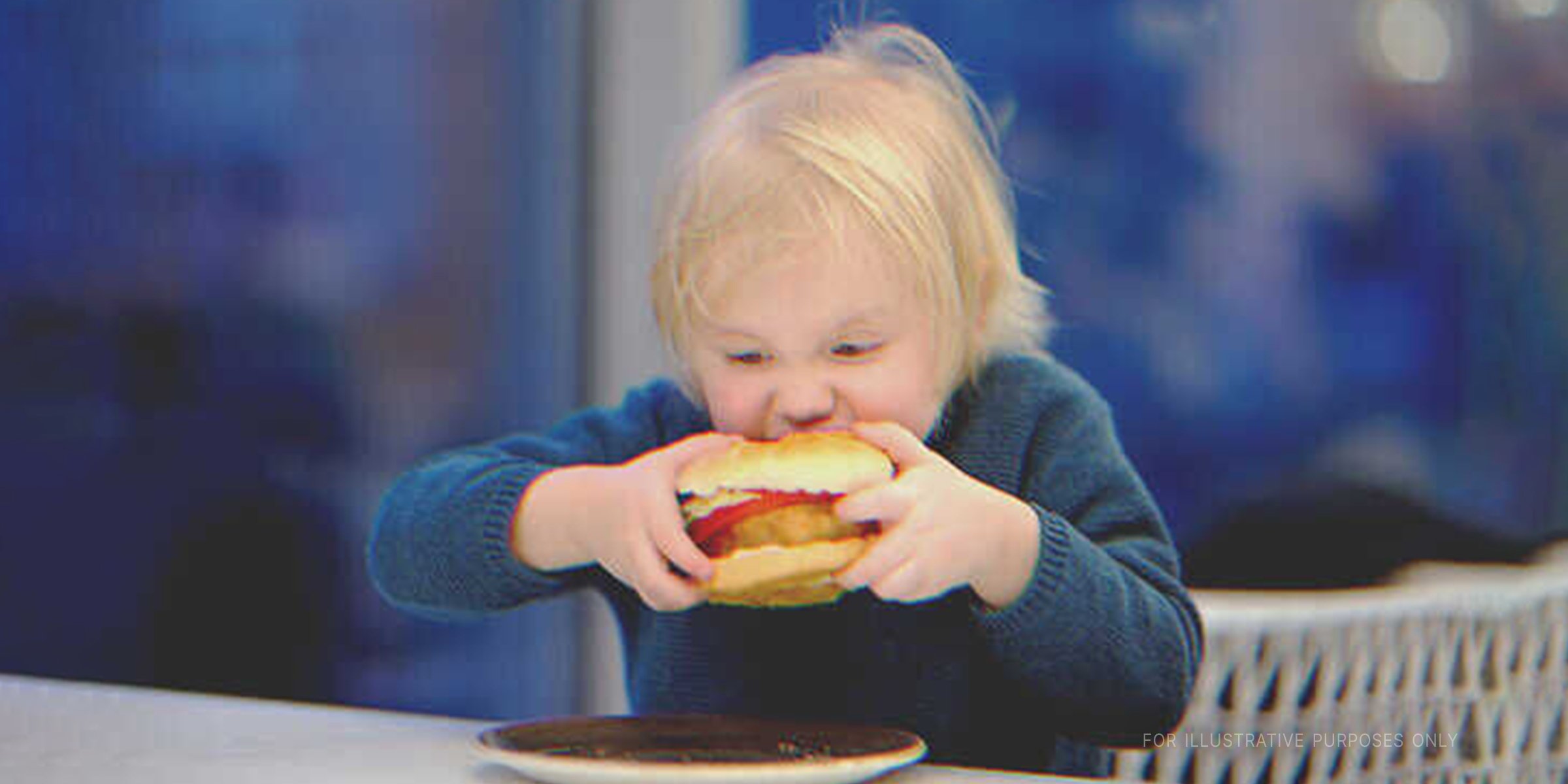 Little kid eating a burger. | Source: Shutterstock