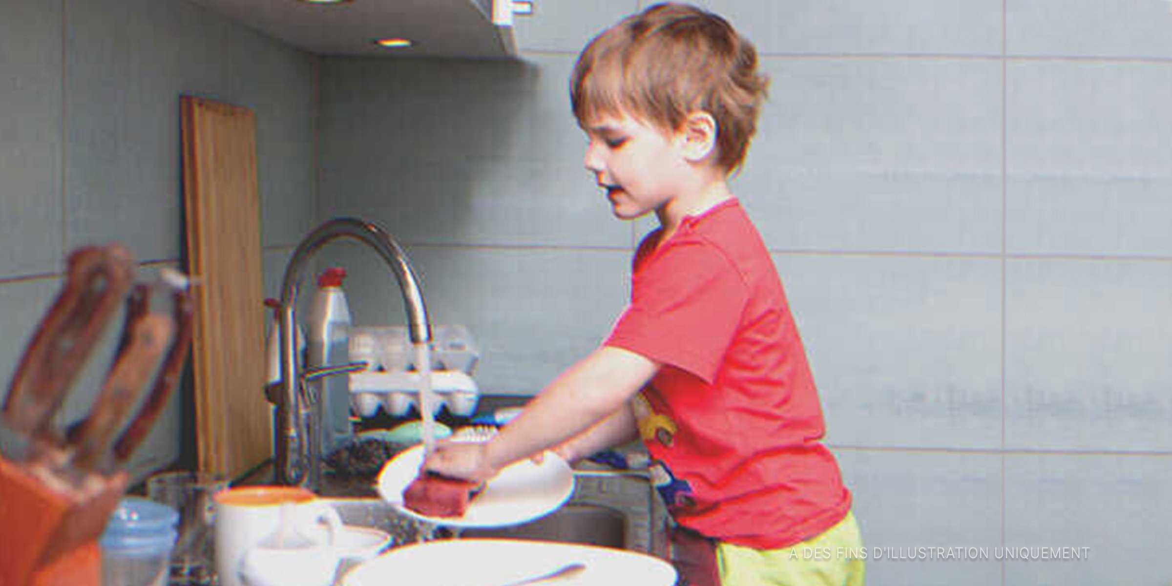 Un peti garçon qui lave les assiettes. | Source : Shutterstock