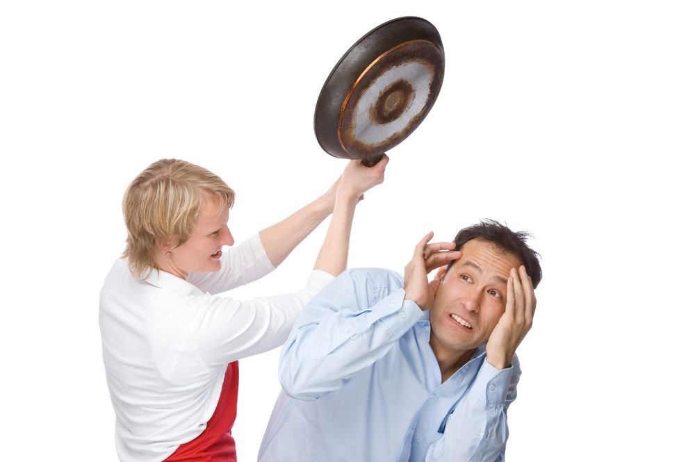 A woman about to hit a man over the head with a frying pan. │ Source: Shutterstock