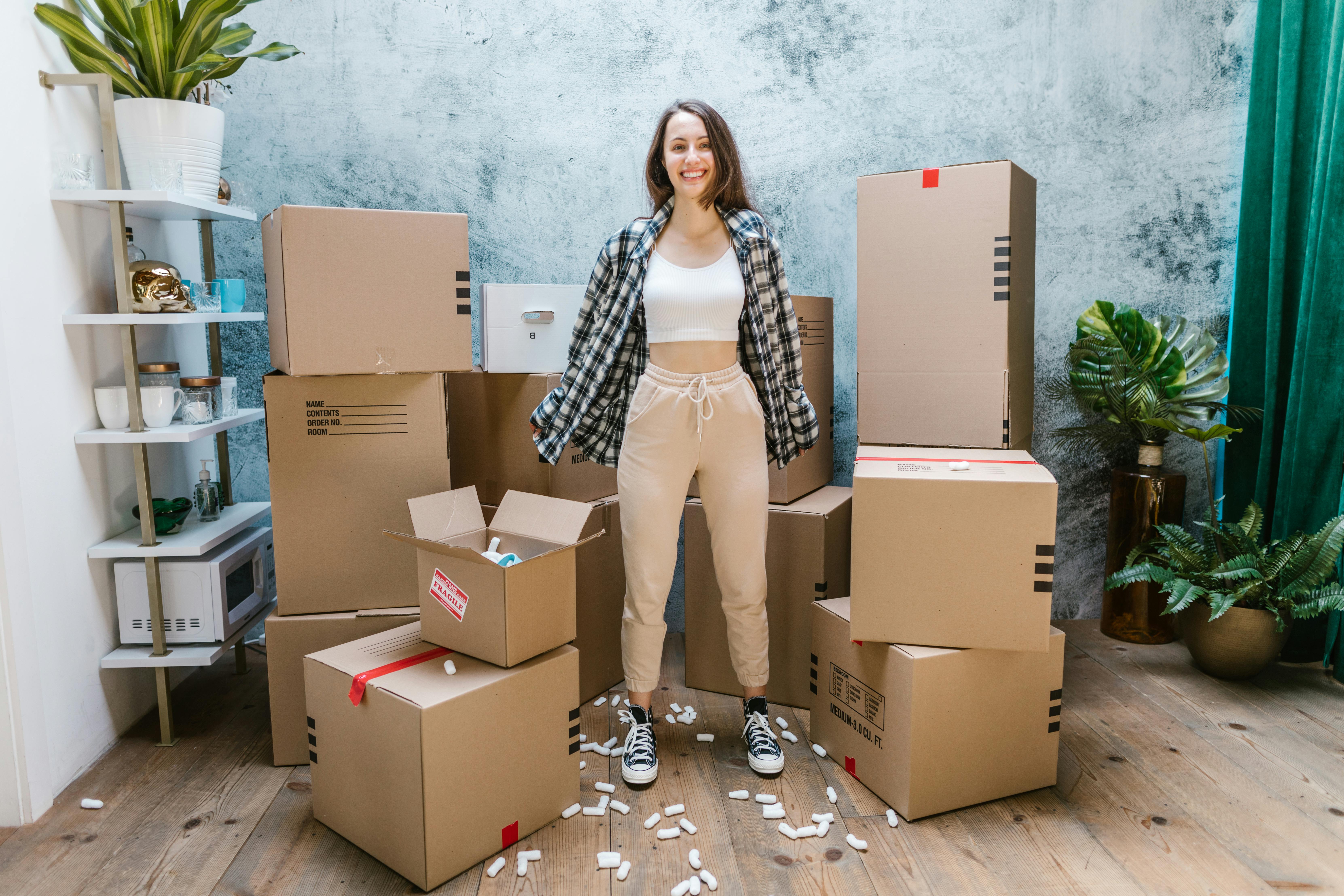 A woman smiling while surrounded by boxes | Source: Pexels