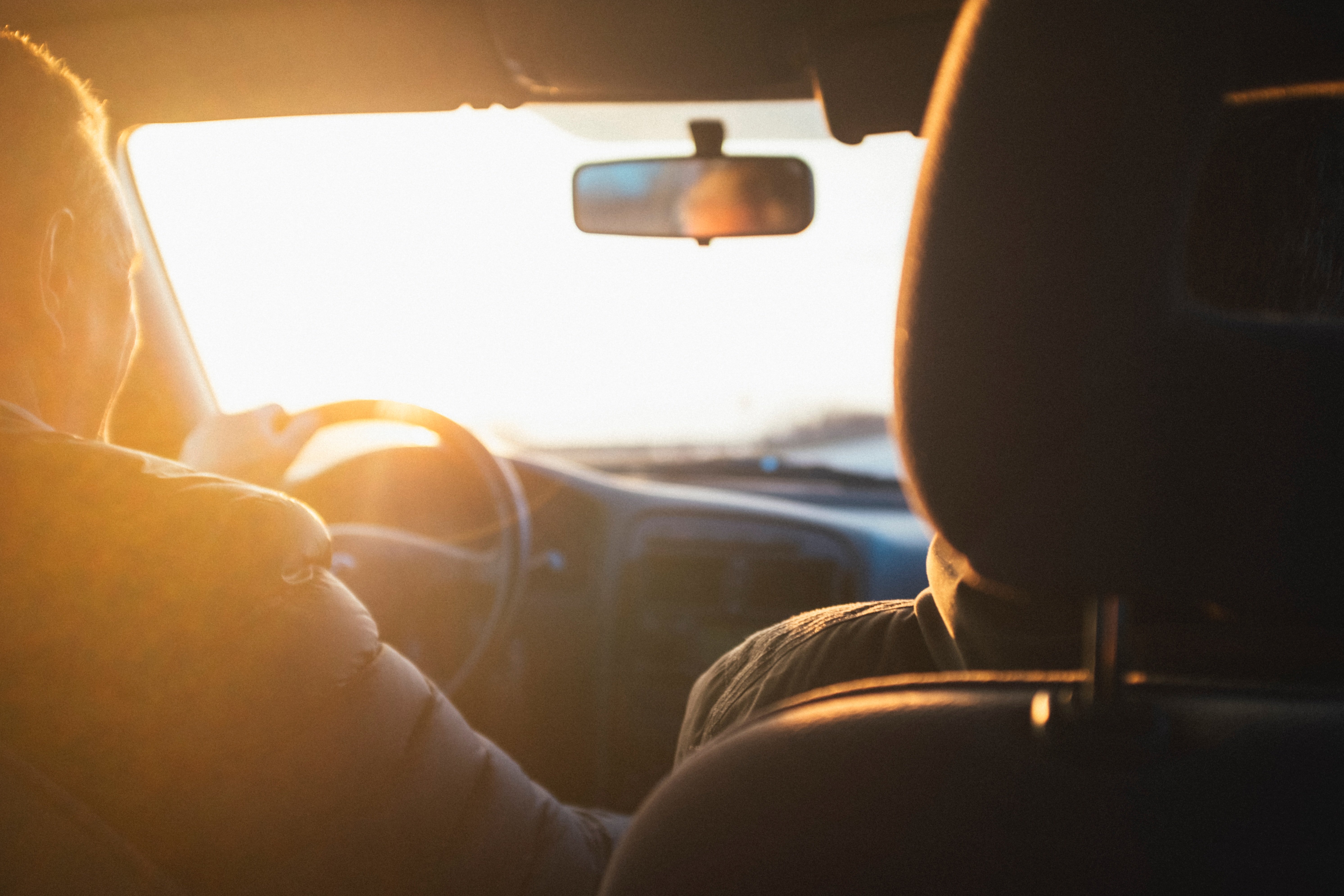 Two people driving in a car at sunset. | Source: Unsplash