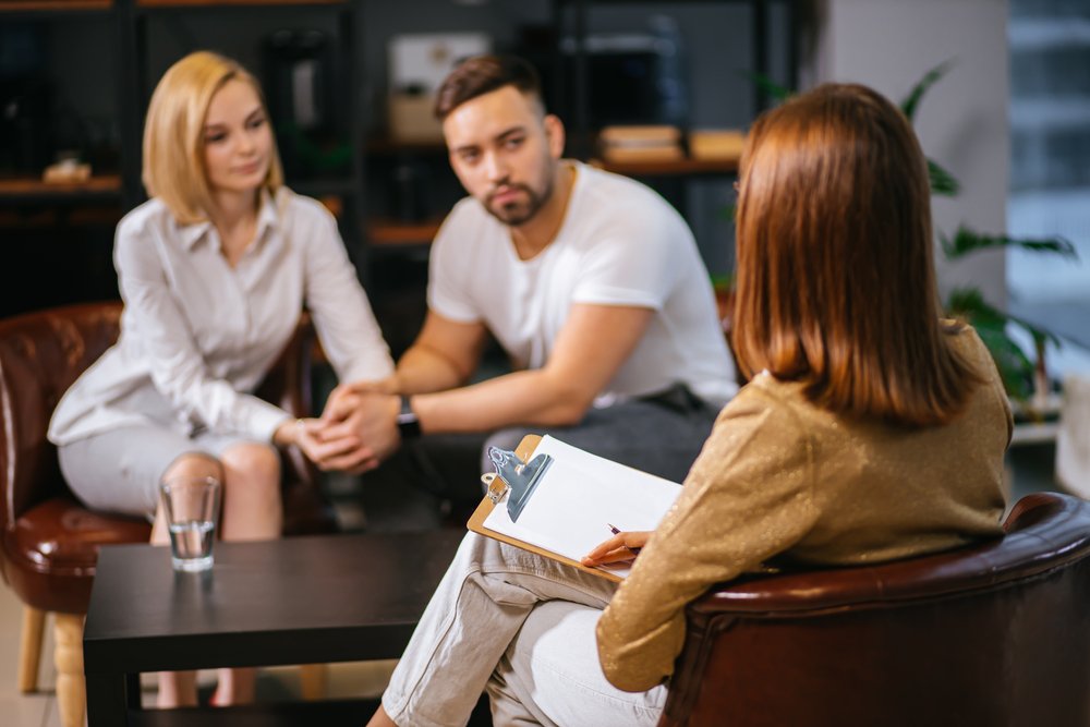 A married couple sitting together in a psychologist office sharing opinions and experiences | Photo: Shutterstock