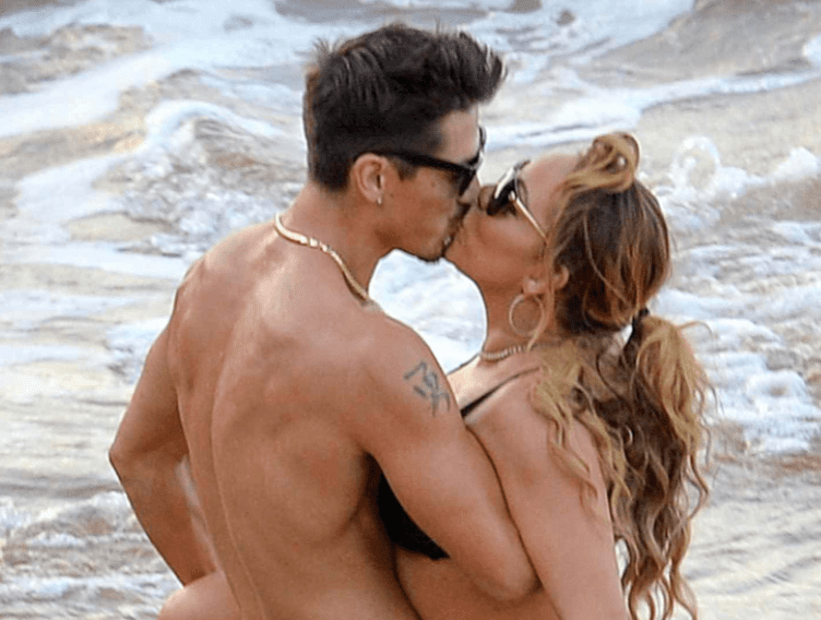 El bailarín Bryan Tanaka y su novia Mariah Carey fotografiados besándose en una playa. | Foto: AKM-GSI