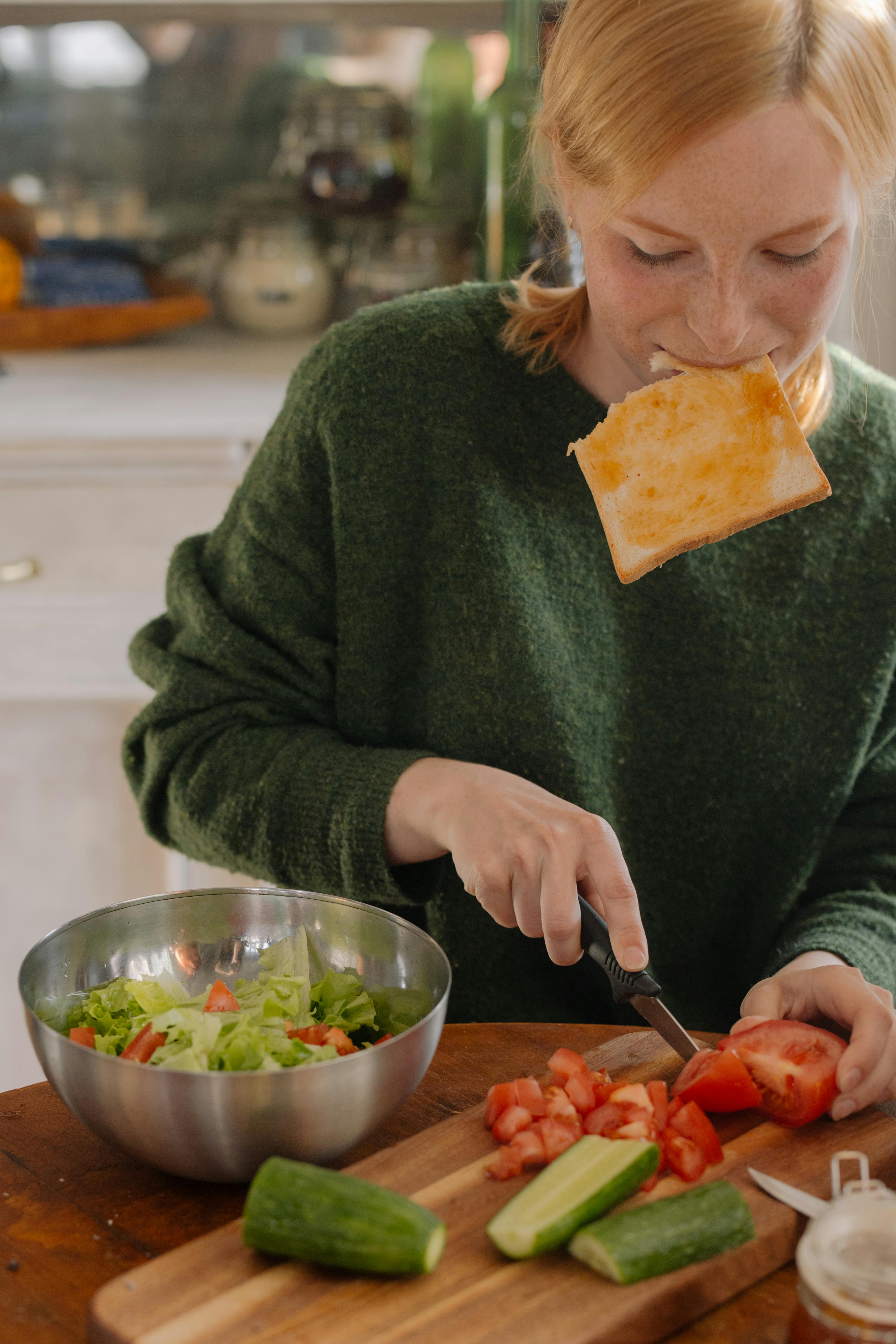 A woman eating and chopping veggies | Source: Pexels