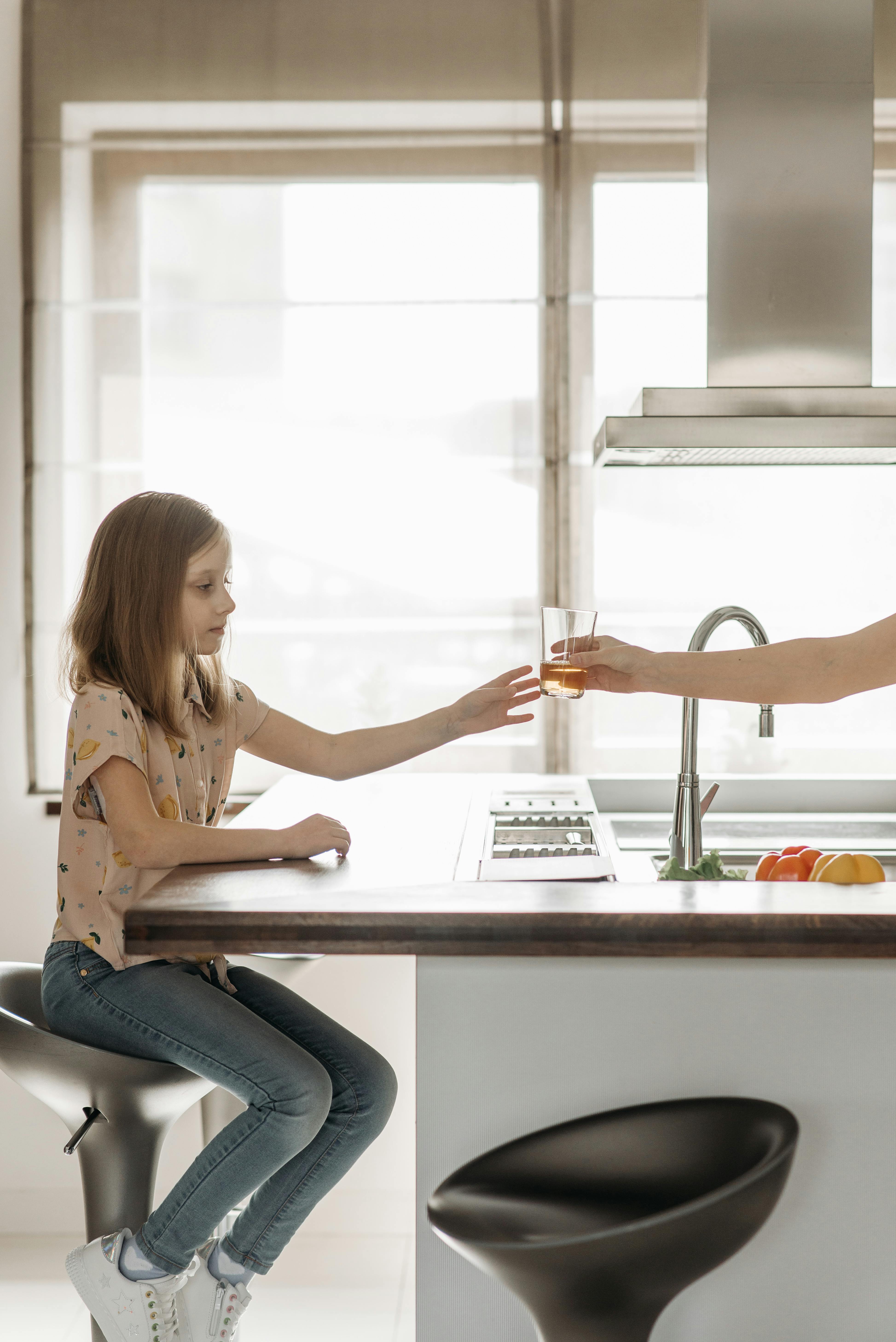 A woman handing over juice to a child | Source: Pexels