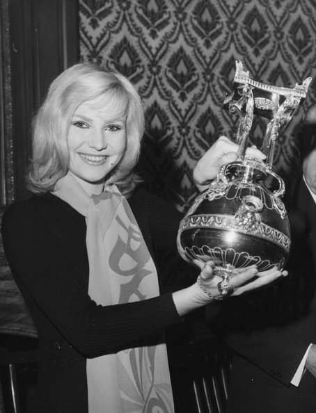 La chanteuse française Michele Torr sourit en tenant le trophée de la Coupe de France de football, vers 1965. | Photo : Getty Images