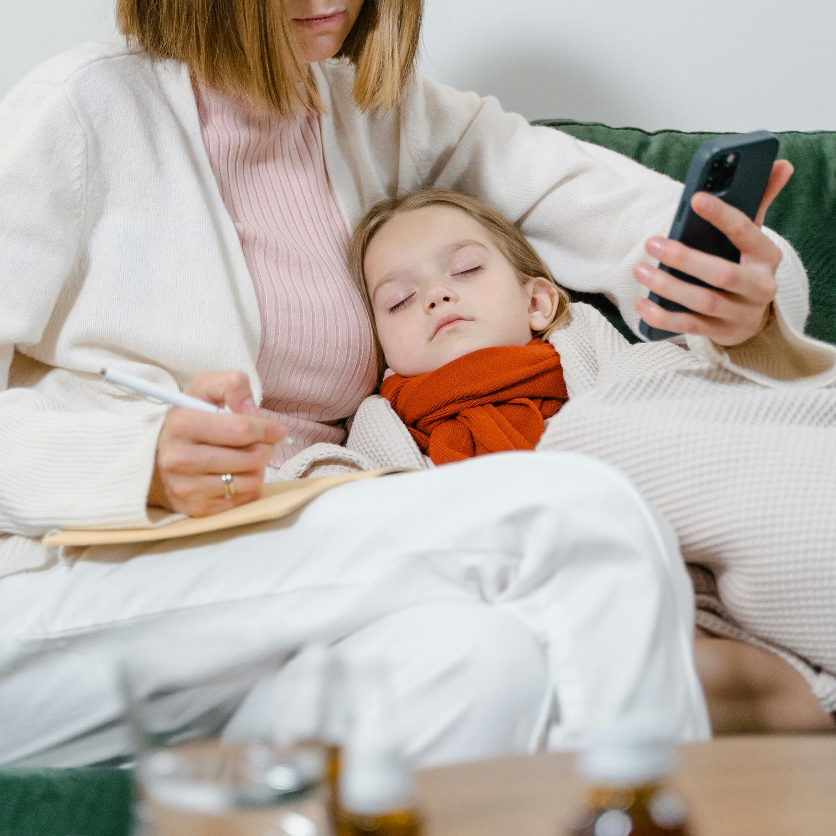 A woman cares for a sick child while making notes | Source: Pexels