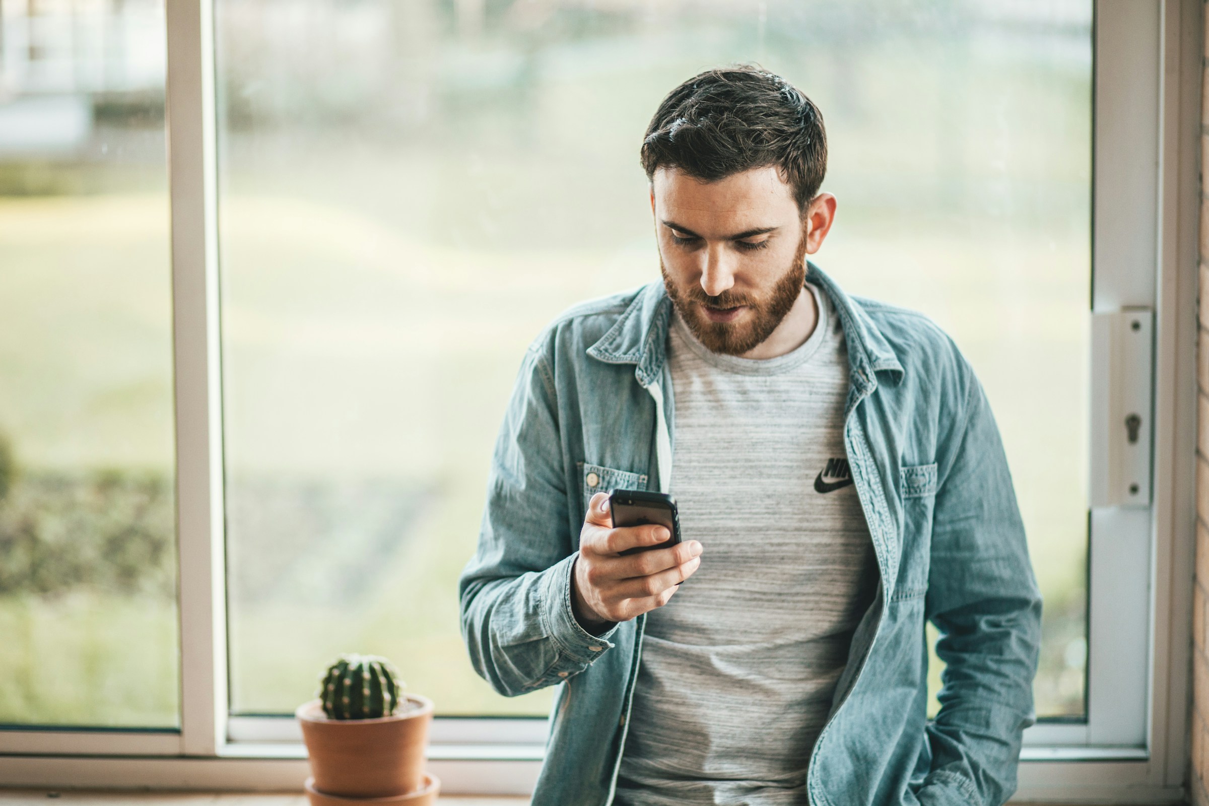 A man holding a smart phone in front of a window | Source: Pexels