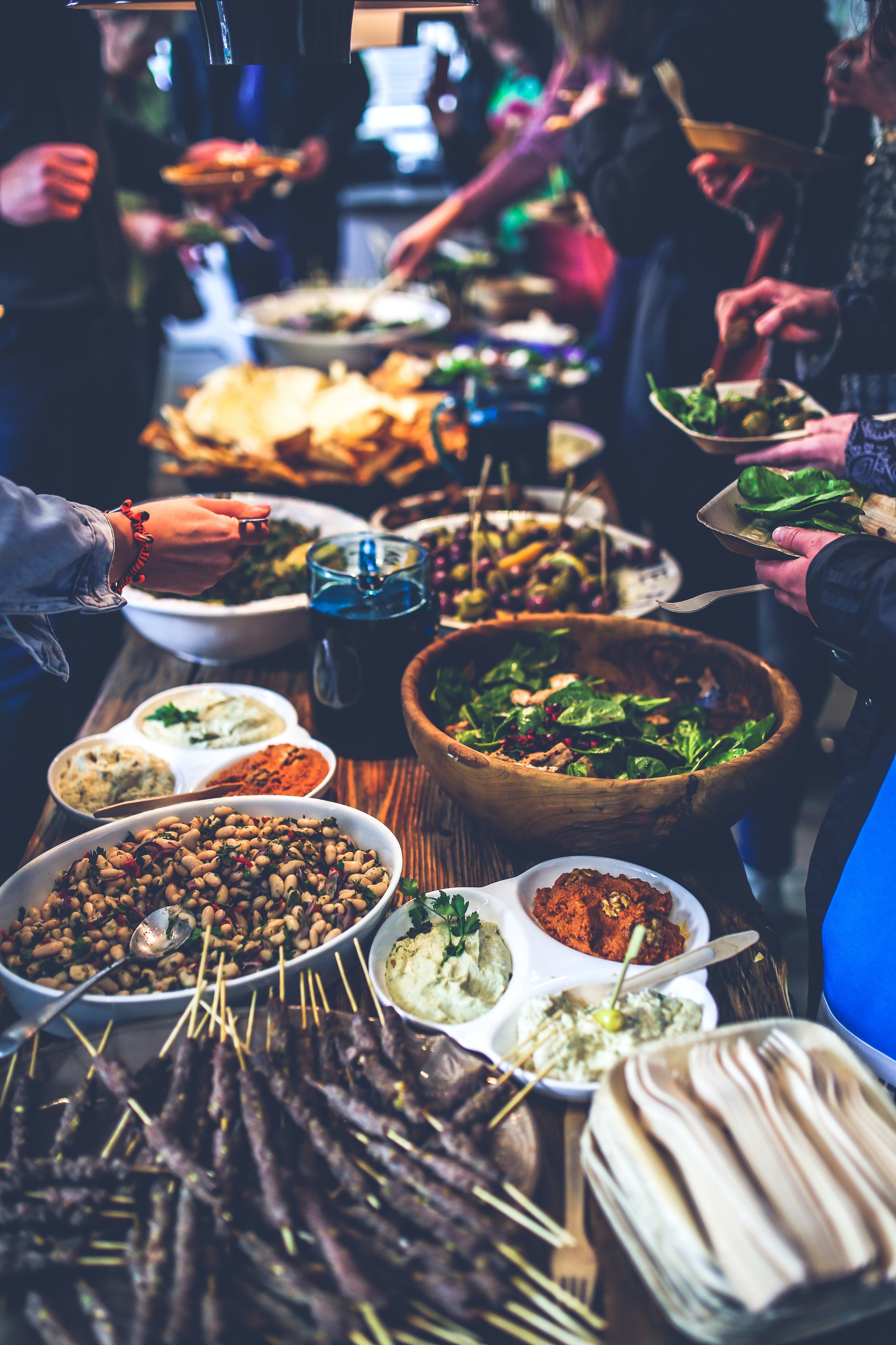 People dishing up at a buffet. | Pexels