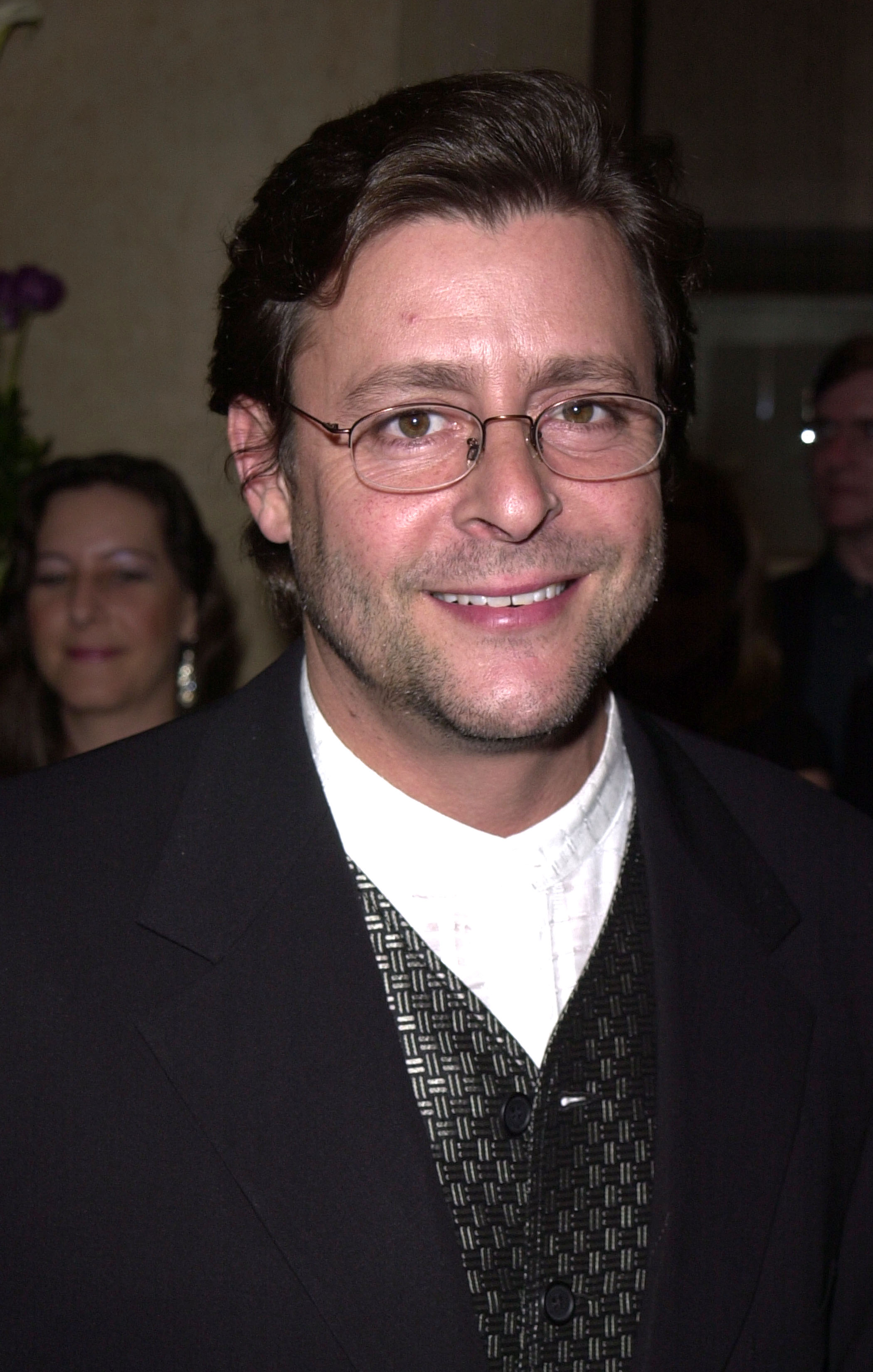 Wearing thin-framed glasses and a patterned vest beneath a dark jacket, the actor flashed a warm smile at the 15th Annual Genesis Awards on March 10, 2001. | Source: Getty Images