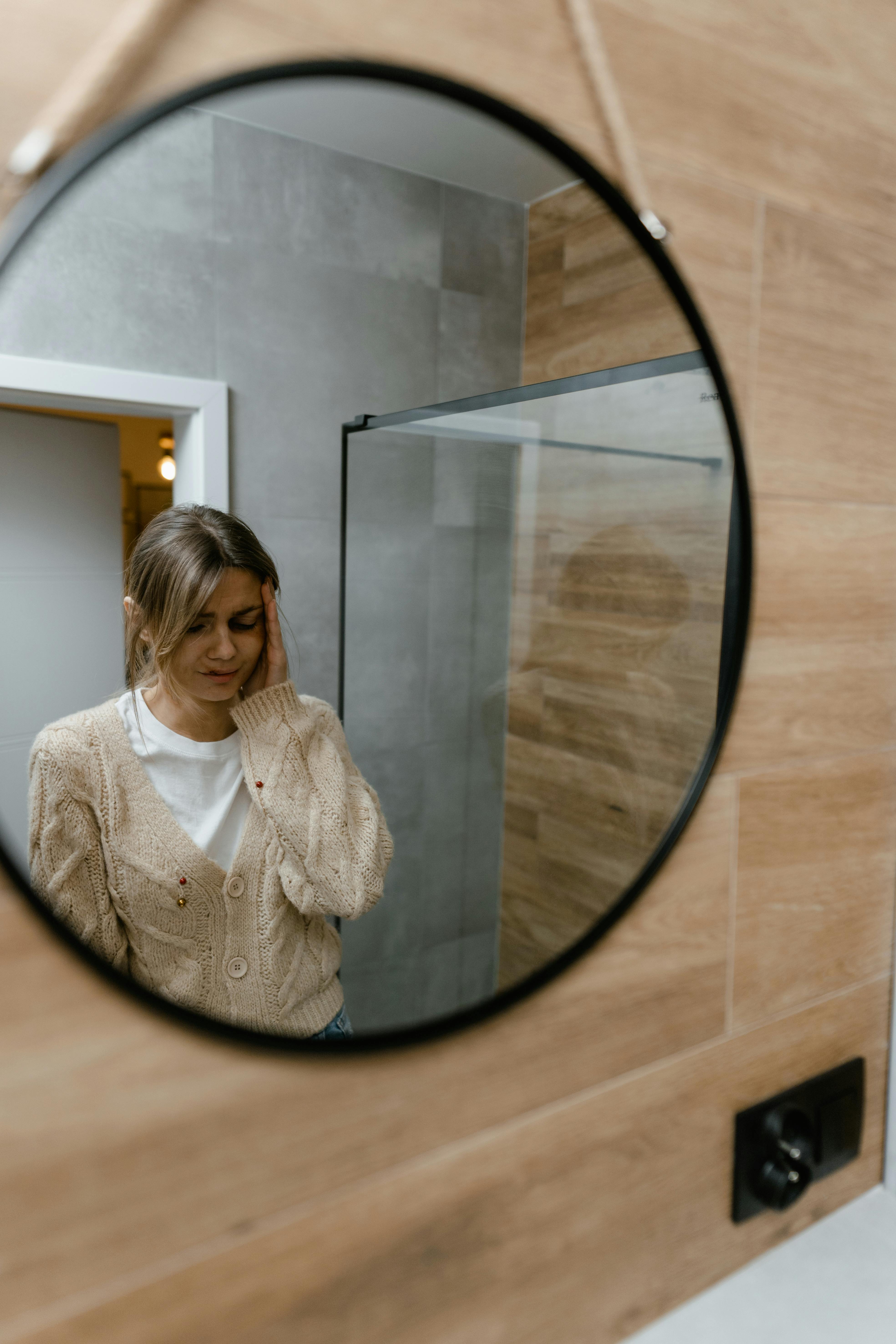 A worried woman looking into the mirror | Source: Pexels